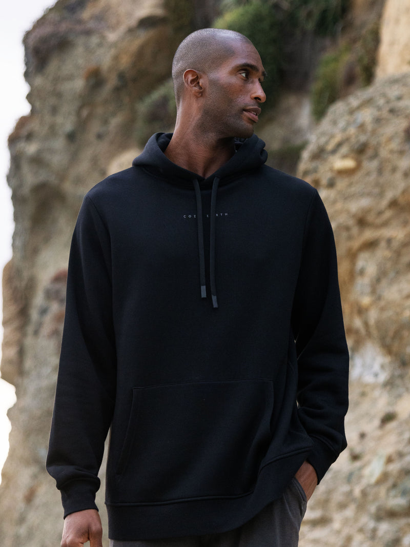 Man wearing black cityscape hoodie with rocky backdrop
