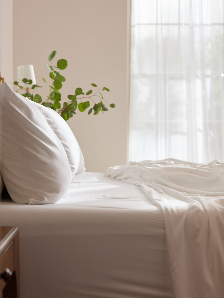 Side view of unmade bed with white bedding |Color:White
