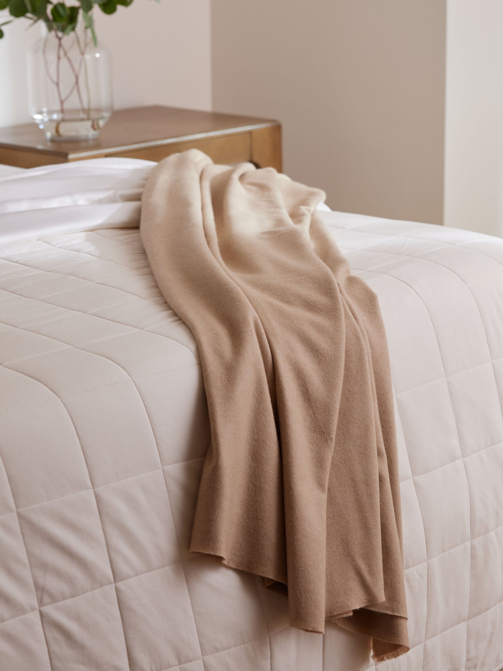 Dune Fringe blanket draped on bed with white comforter 