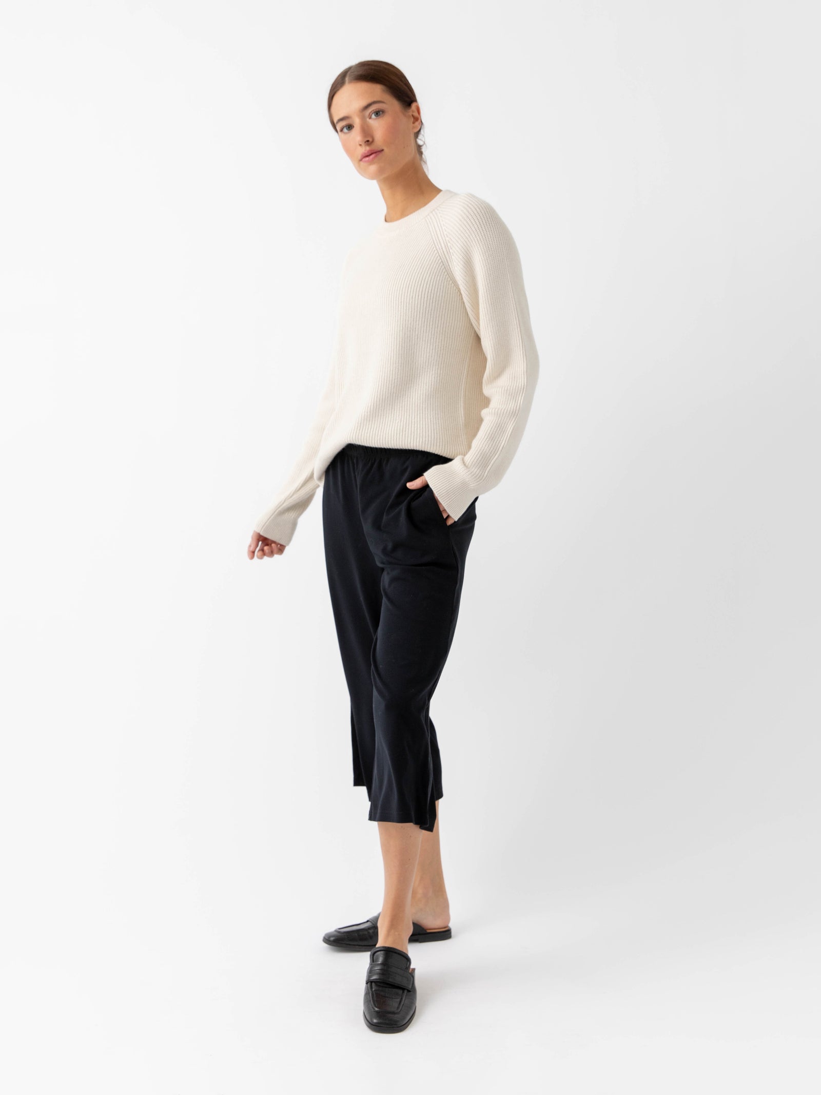 Woman wearing alabaster classic crewneck and black pants with white background 