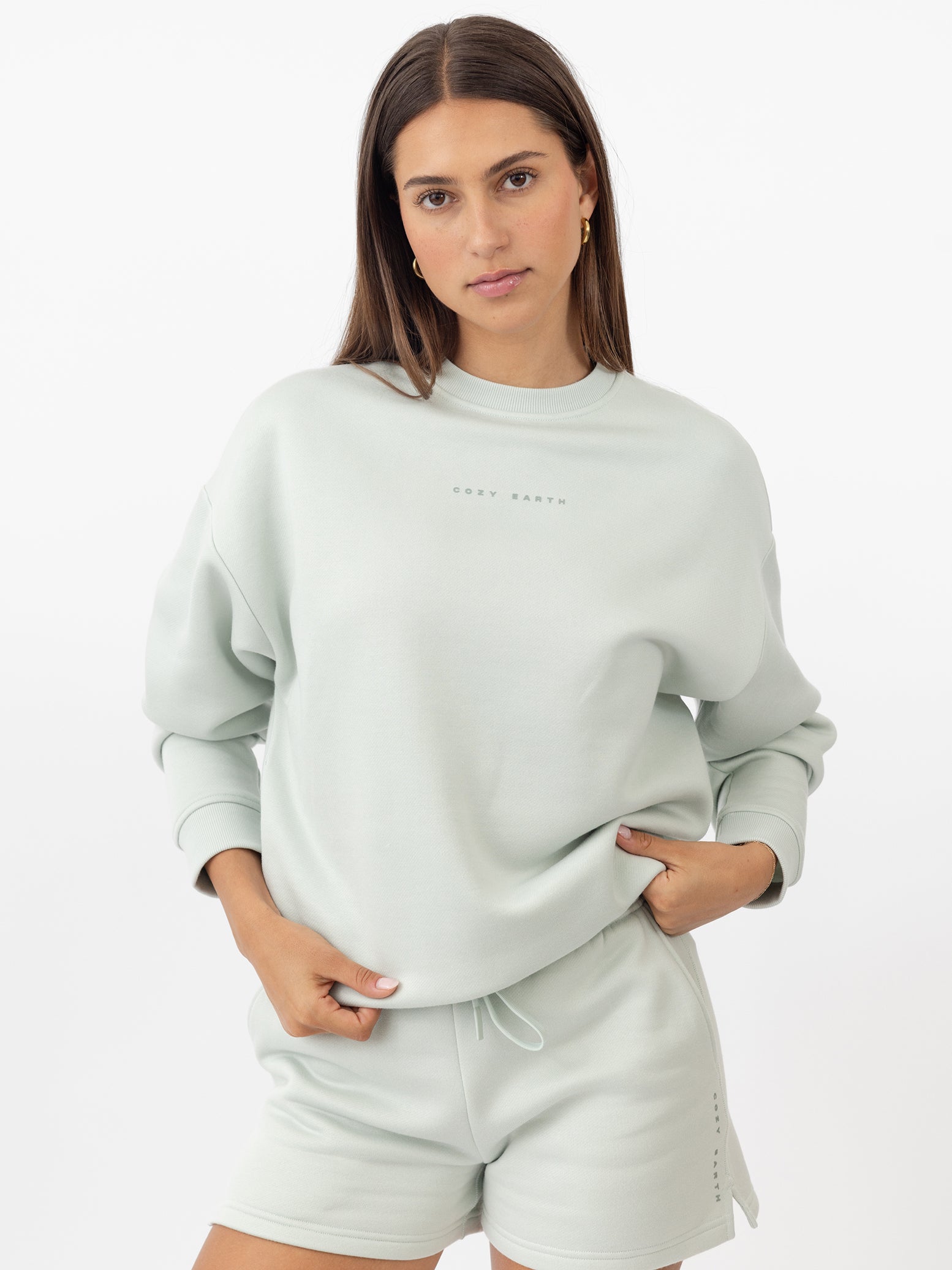Arctic CityScape Pullover Crew. The Pullover is being worn by a female model. Accompanying city scape clothing is being worn to complete the look of the outfit. The photo was taken with a white background. |Color:Arctic