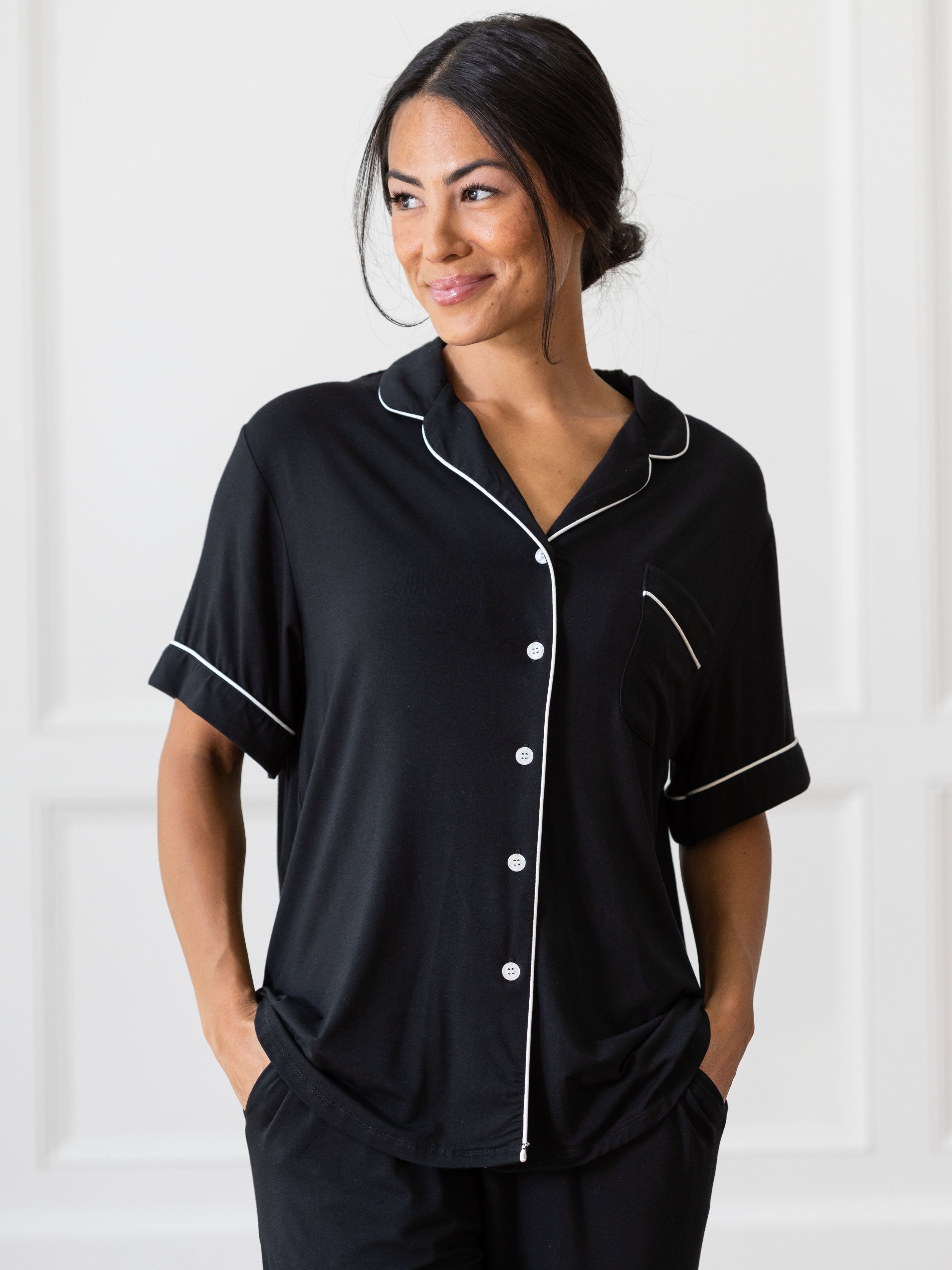 Black Short Sleeve & Pant Bamboo Pajama Set modeled by a woman. The photo was taken in a high contrast setting, showing off the colors and lines of the pajamas. |Color: Black