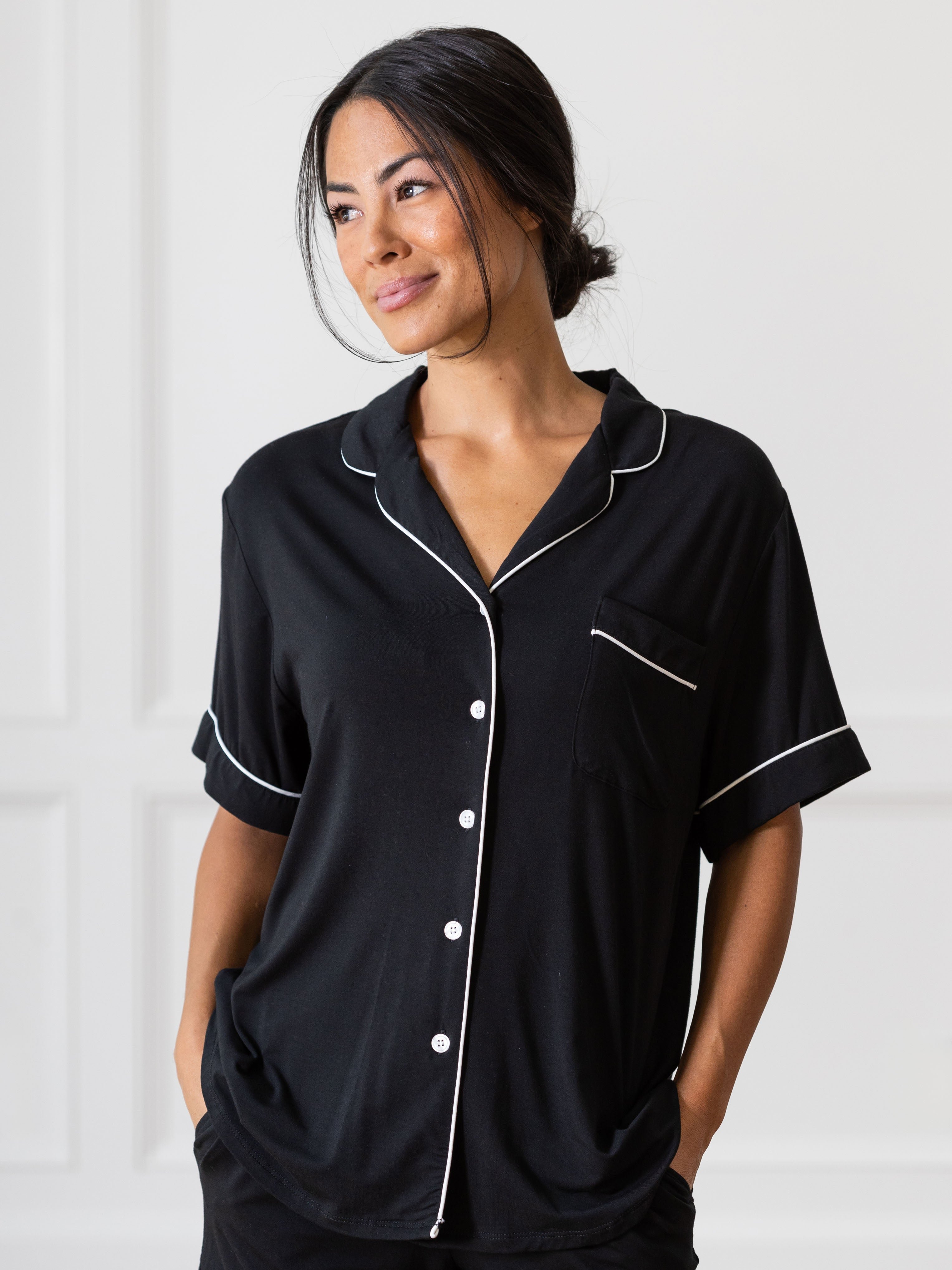 Black Short Sleeve Pajama Set modeled by a woman. The photo was taken in a light setting, showing off the colors and lines of the pajamas. 