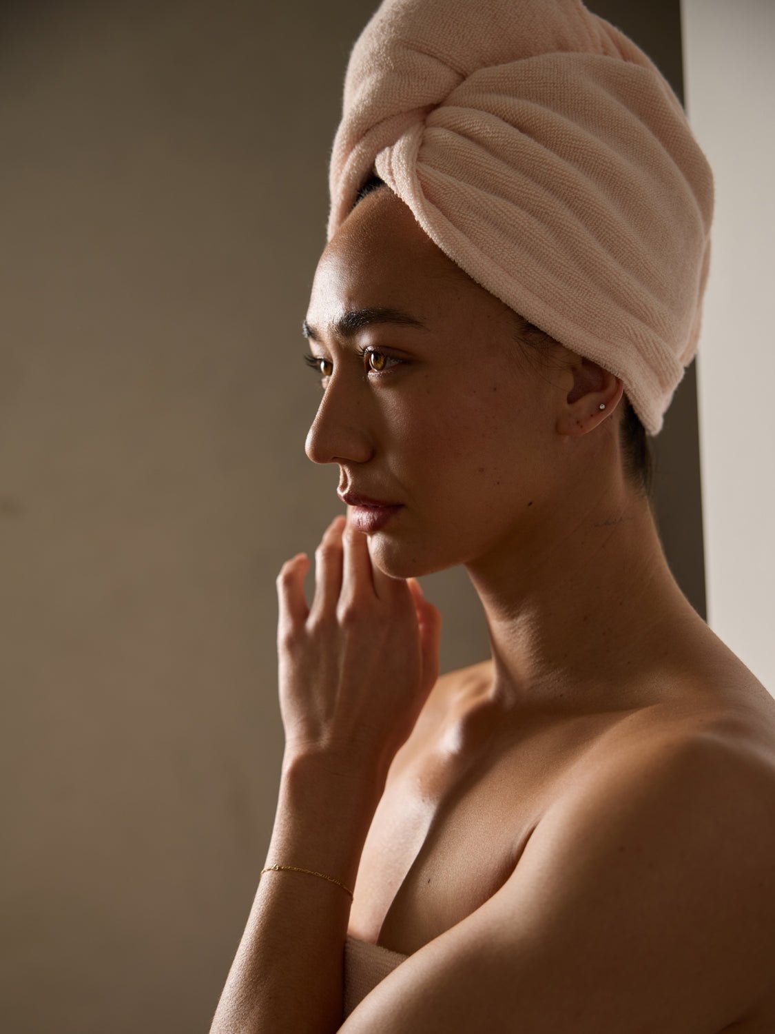 A woman turned to the side is shown from the shoulders up wearing a Cozy Earth Luxe Hair Towel in Blossom. 