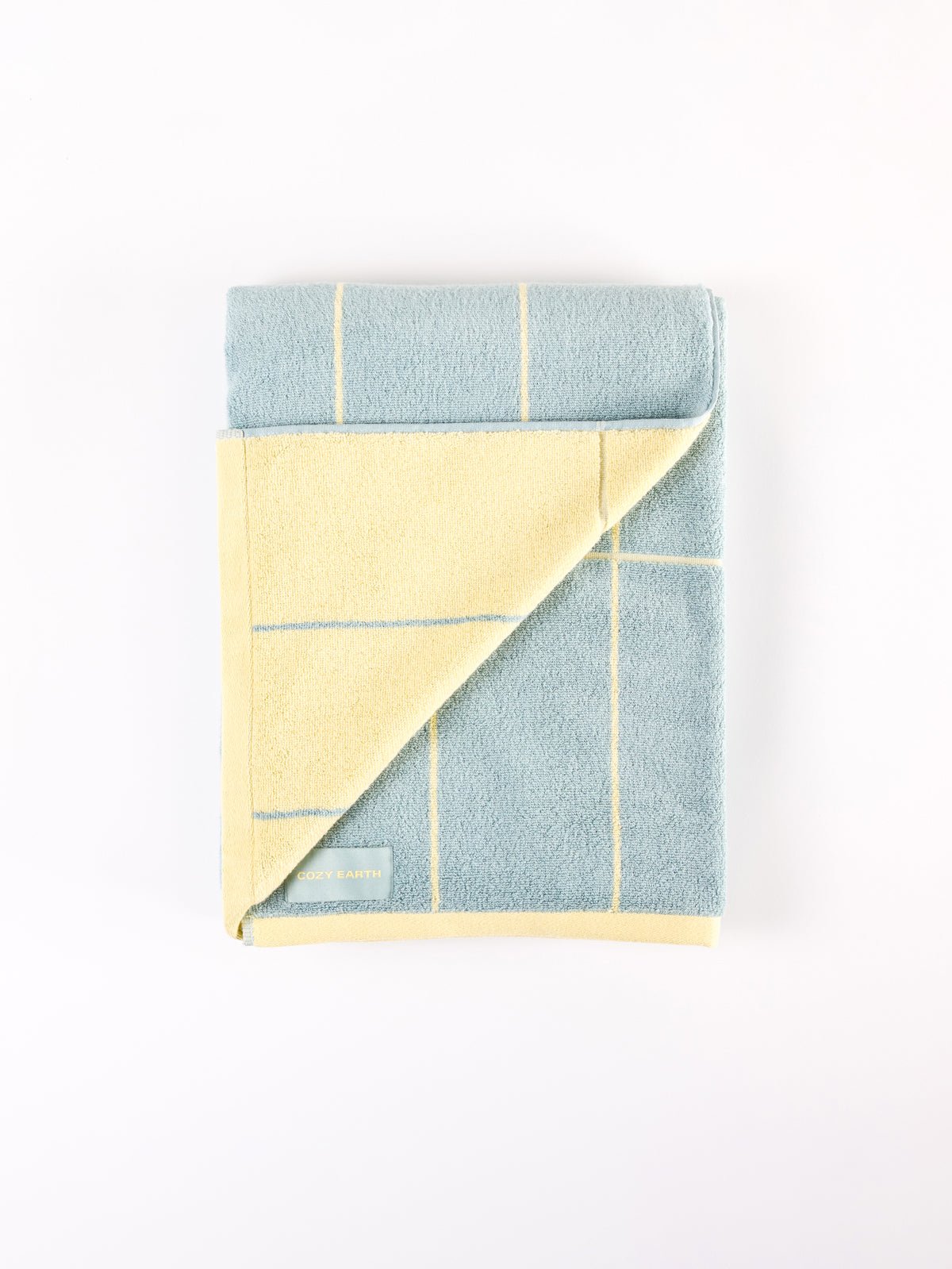 The Cozy Earth Windowpane Resort Towel, folded to reveal its blue side with yellow lines atop and the yellow side with blue lines underneath, is neatly arranged on a plain white background. |Color:Blue Lagoon