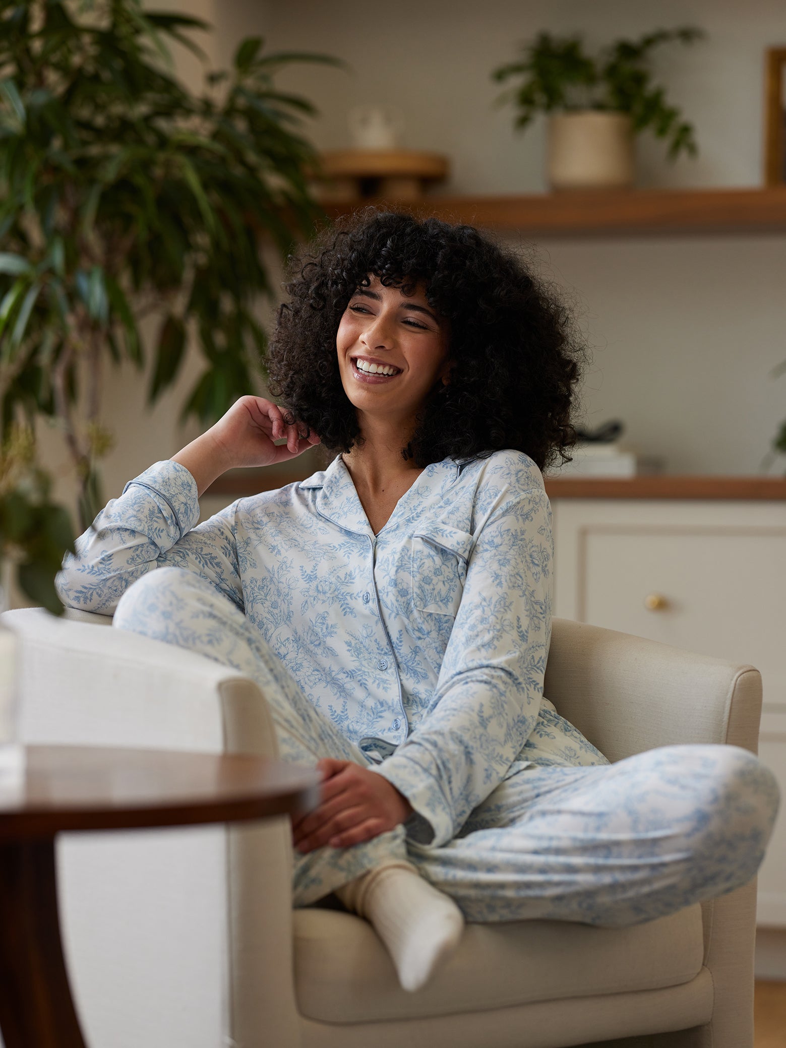 Woman sitting in living room in blue toile pajama set 