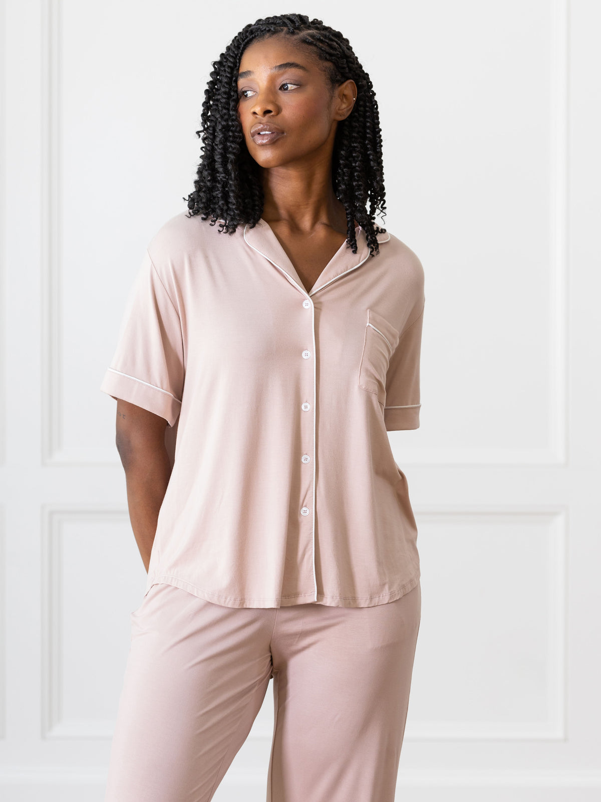 Blush Short Sleeve & Pant Bamboo Pajama Set modeled by a woman. The photo was taken in a high contrast setting, showing off the colors and lines of the pajamas. 
