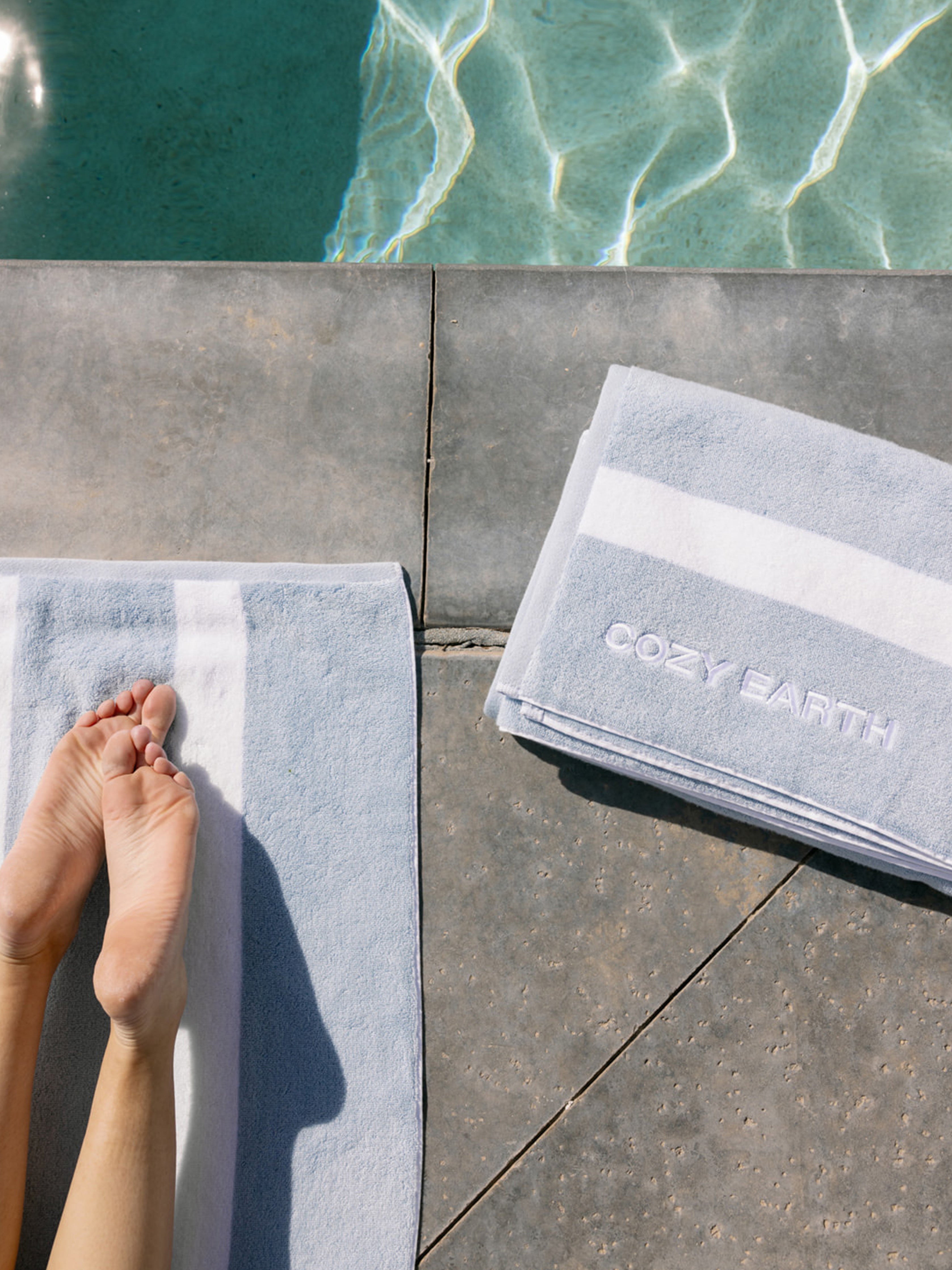 Two Cozy Earth breeze resort towels next to the pool |Color:Breeze
