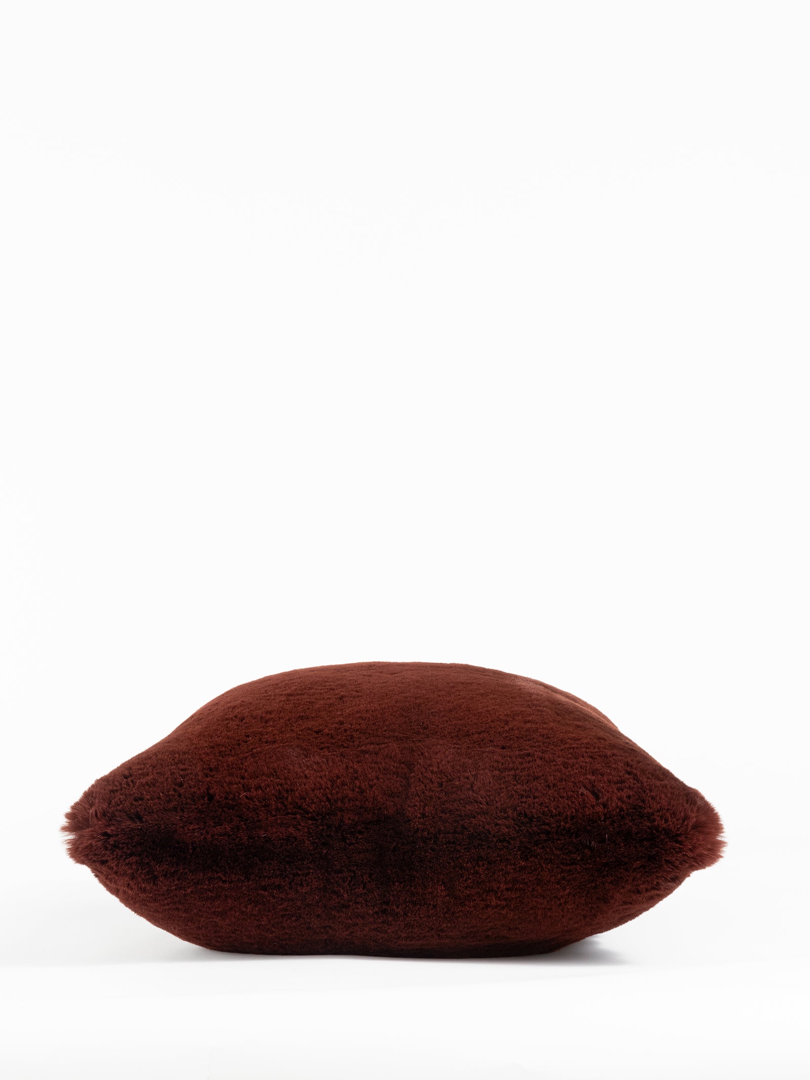 A soft, fluffy Cuddle Pillow in dark brown by Cozy Earth is centered against a plain white background. 