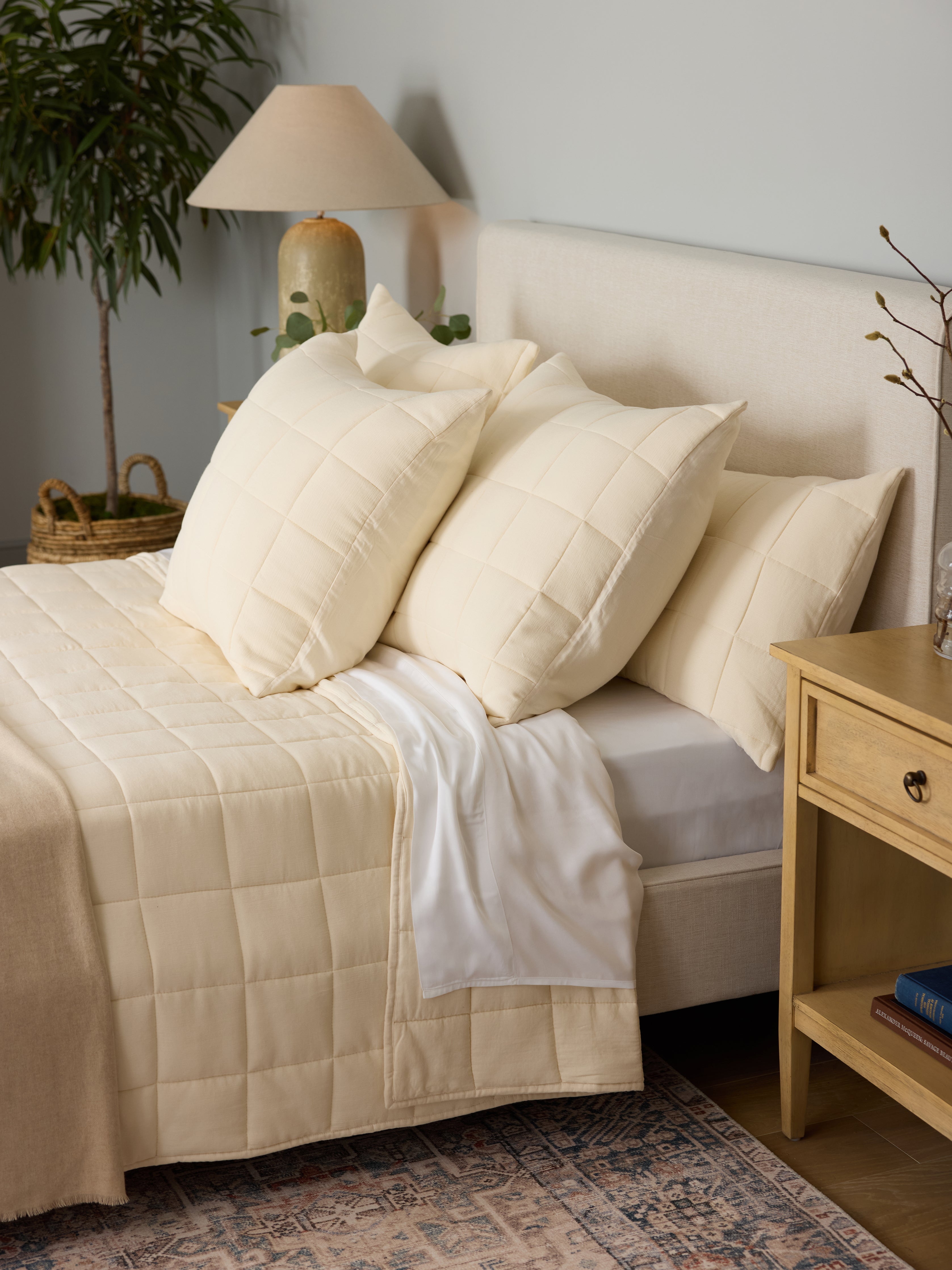 Buttermilk Aire Bamboo Box Quilt Euro Sham. The sham is resting on a bed in a bedroom|Color:Buttermilk|Size:King