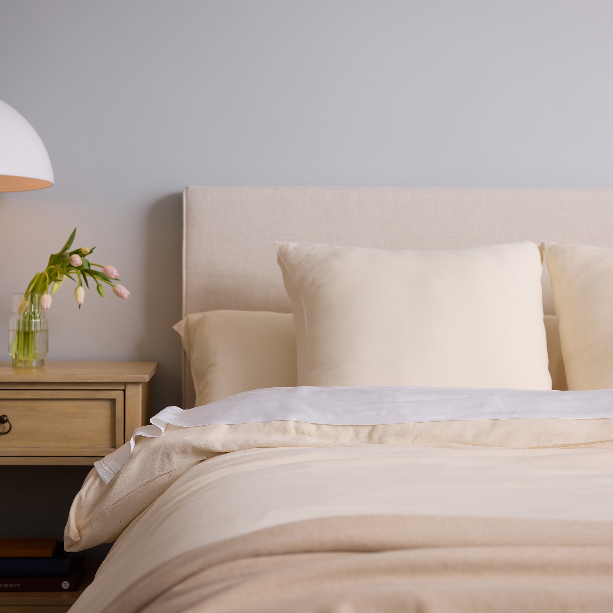 Buttermilk Aire Bamboo Shams. The shams are resting on a bed in a bedroom|Color:Buttermilk|Size:Euro