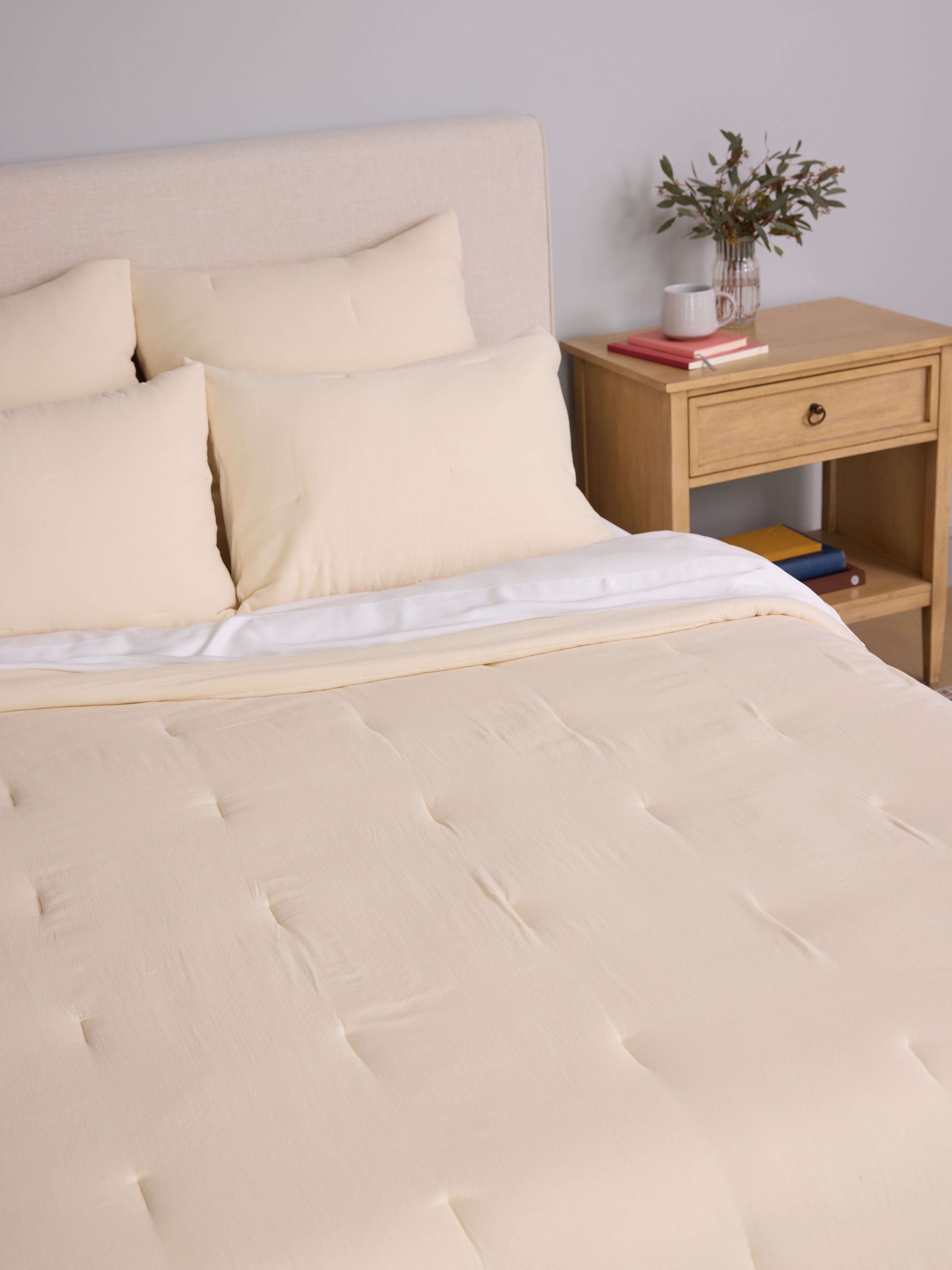 Buttermilk Aire Bamboo Puckered Shams. The shams are resting on a bed in a bedroom|Color:Buttermilk|Size:Euro