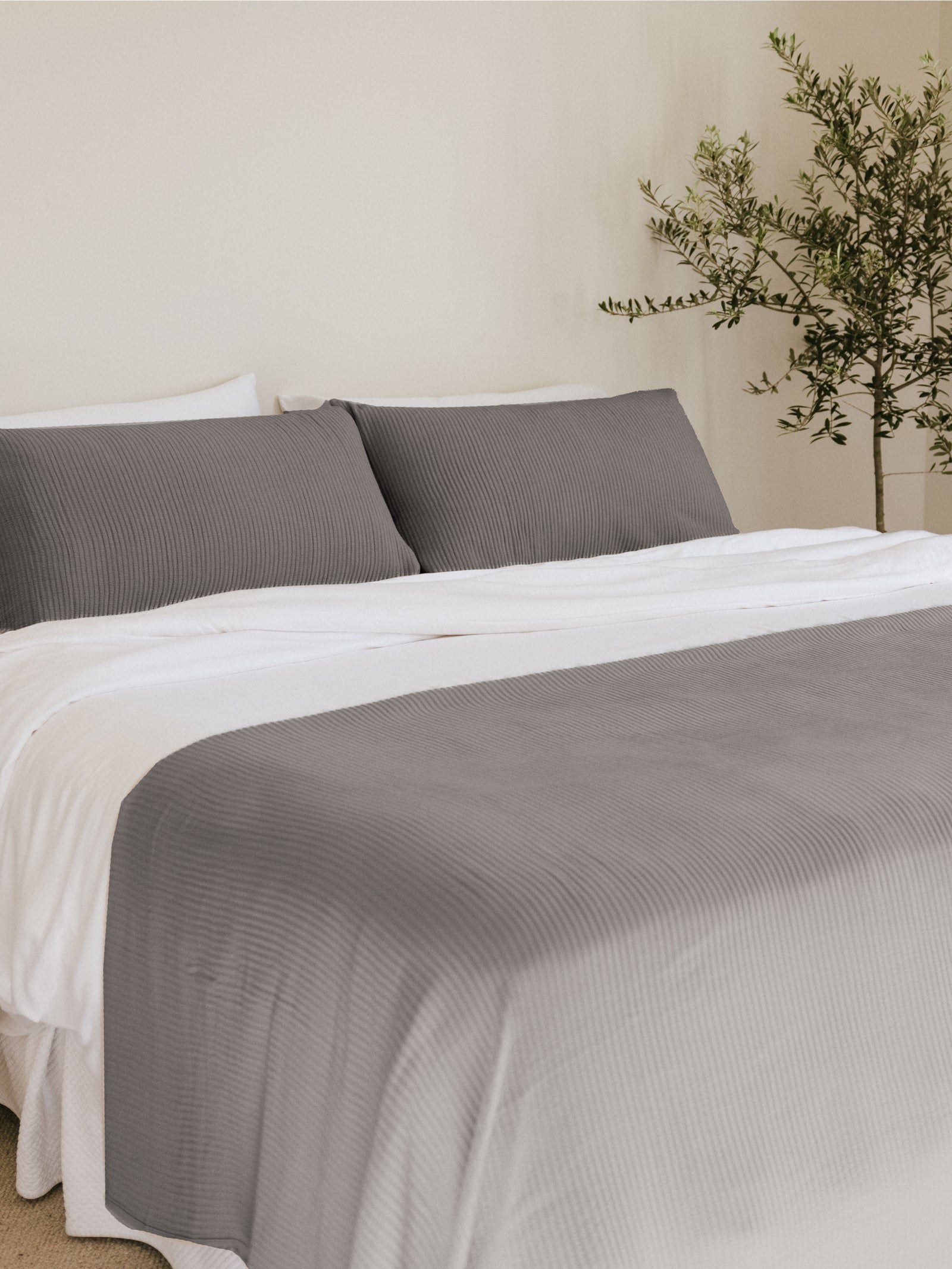 Charcoal coverlet and shams on a bed 