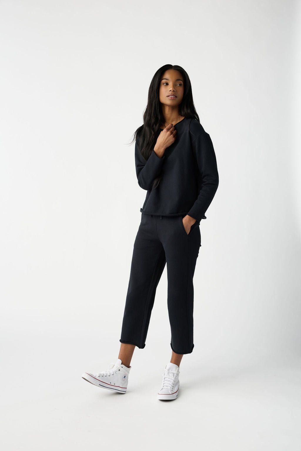 A woman with dark hair wears Cozy Earth Women's Chelsea Cropped Pant in Jet Black in front of a white background. |Color:Jet Black