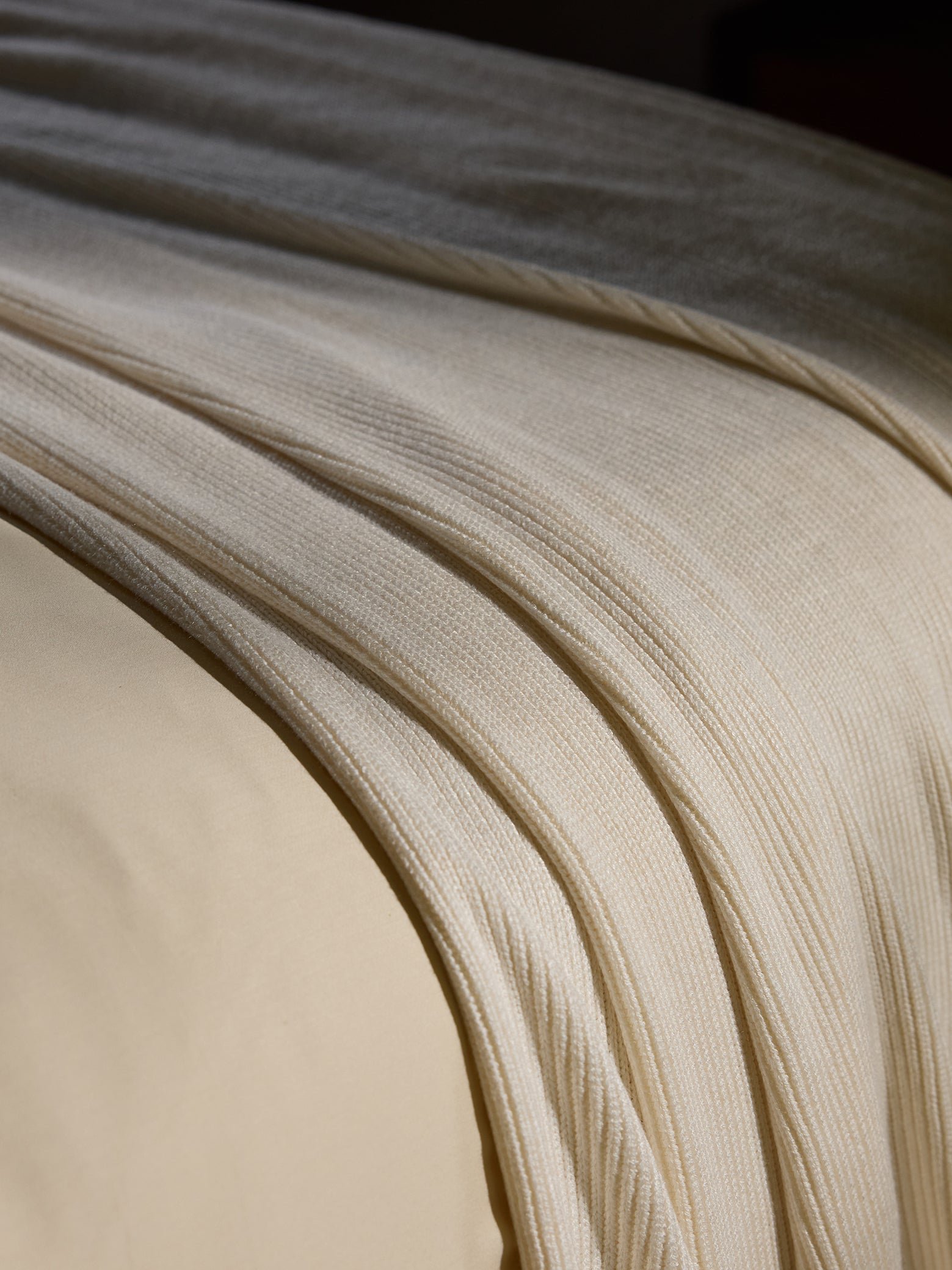 Creme Classic Knit Blanket draped over a bed. |Color:Creme