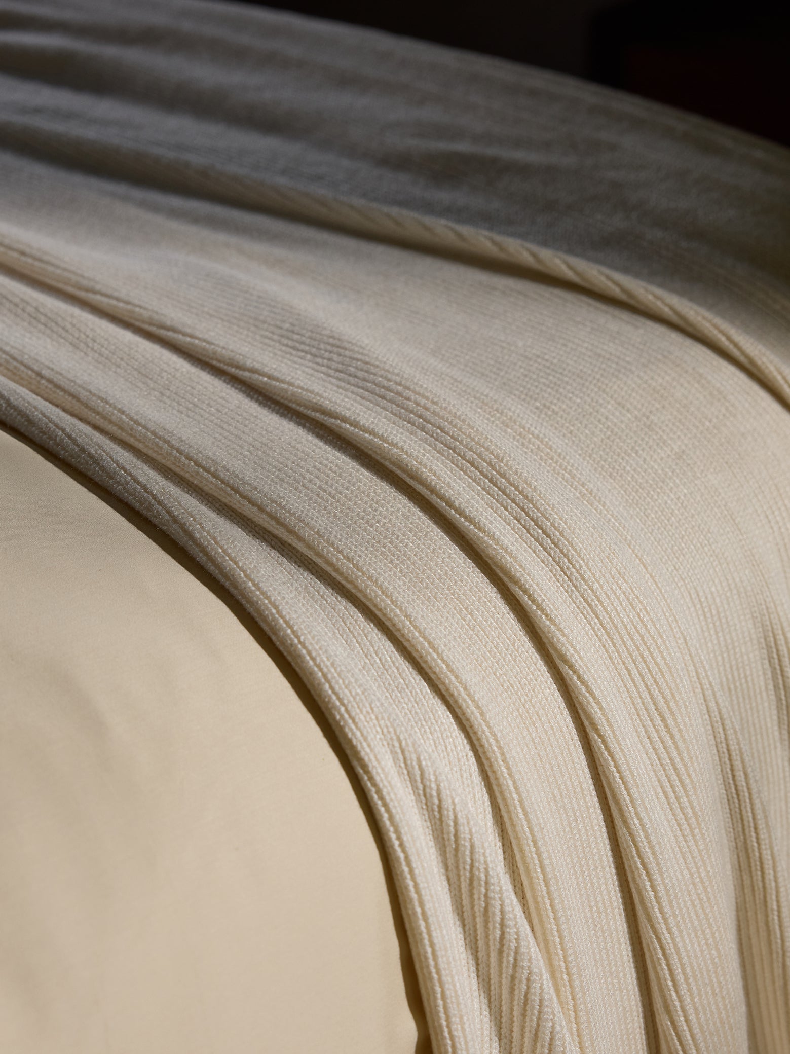 Creme Classic Knit Blanket draped over a bed. 