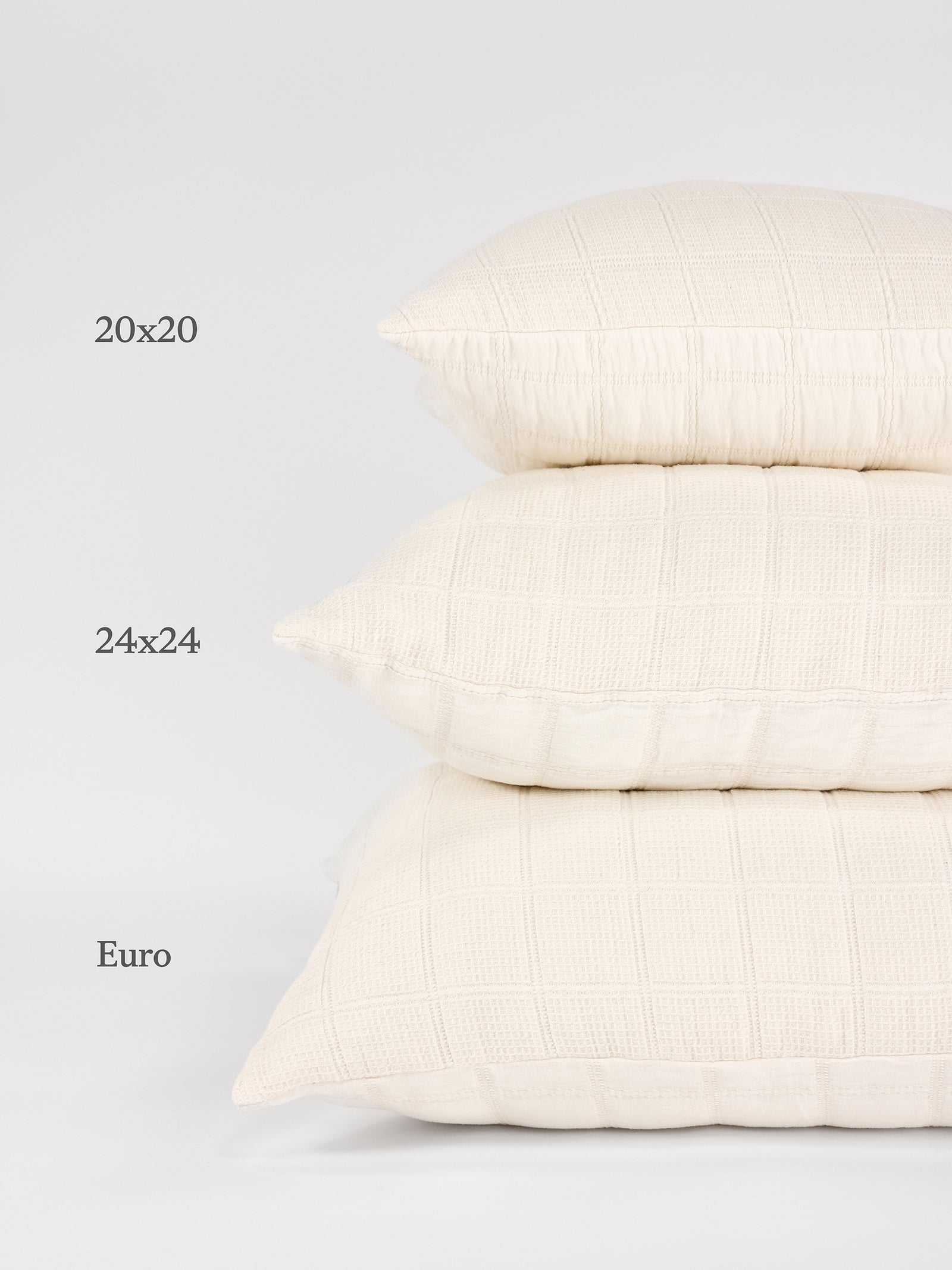 A stack of three Cozy Earth Waffle Windowpane Pillows in different sizes against a white background. The top pillow is labeled "20x20," the middle pillow is labeled "24x24," and the bottom pillow is labeled "Euro. 