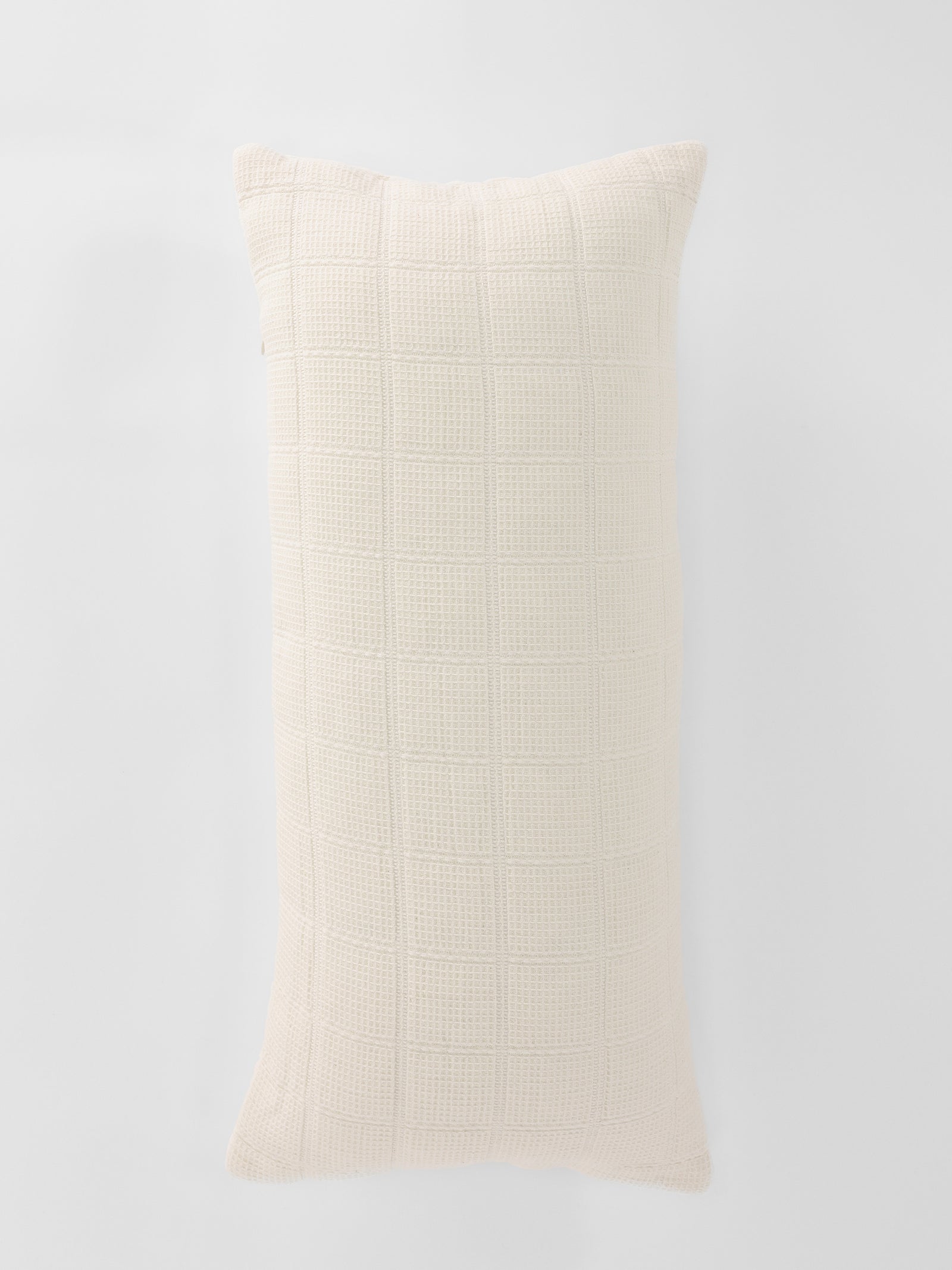 The Cozy Earth Waffle Windowpane Pillow, featuring a long and rectangular design in a cream color with a textured grid pattern, is displayed against a white background. The pillow looks soft and plush, making it ideal for both decorative and comfort purposes. 