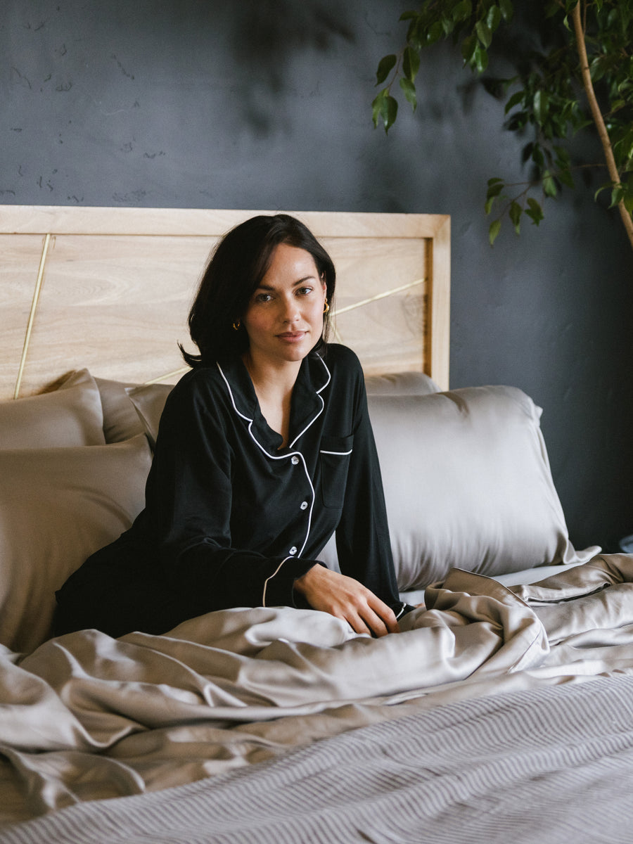 Woman in black pajamas sitting in bed with dove grey sheets |Color:Dove Grey