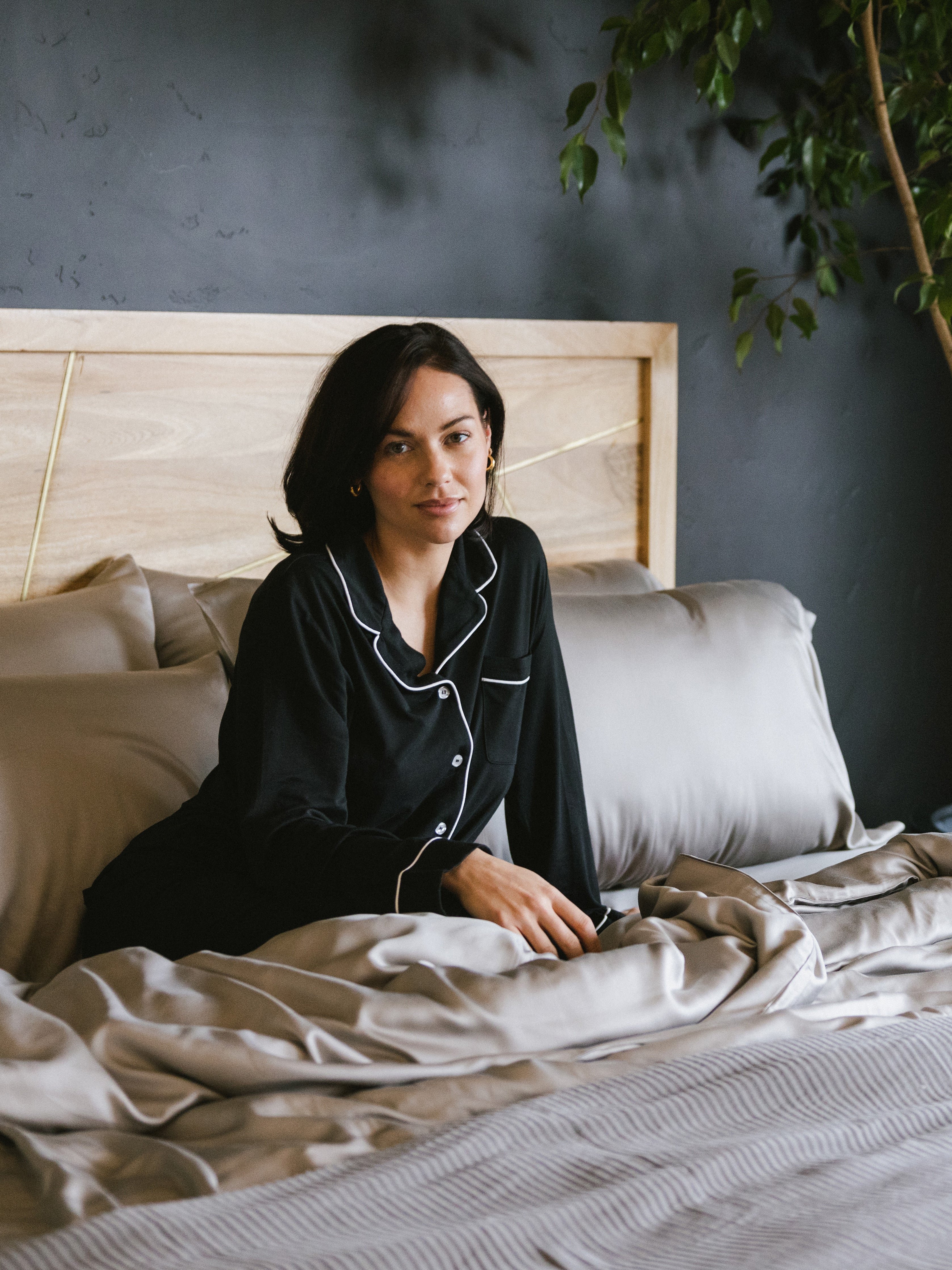 Woman sitting in bed with dove grey sheets 