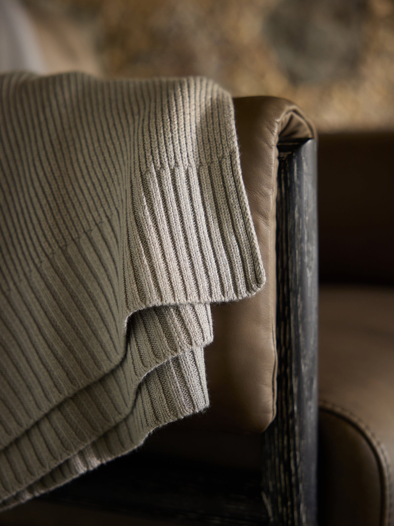 Close up of Dove Grey Classic Knit Blanket draped over a leather chair. 