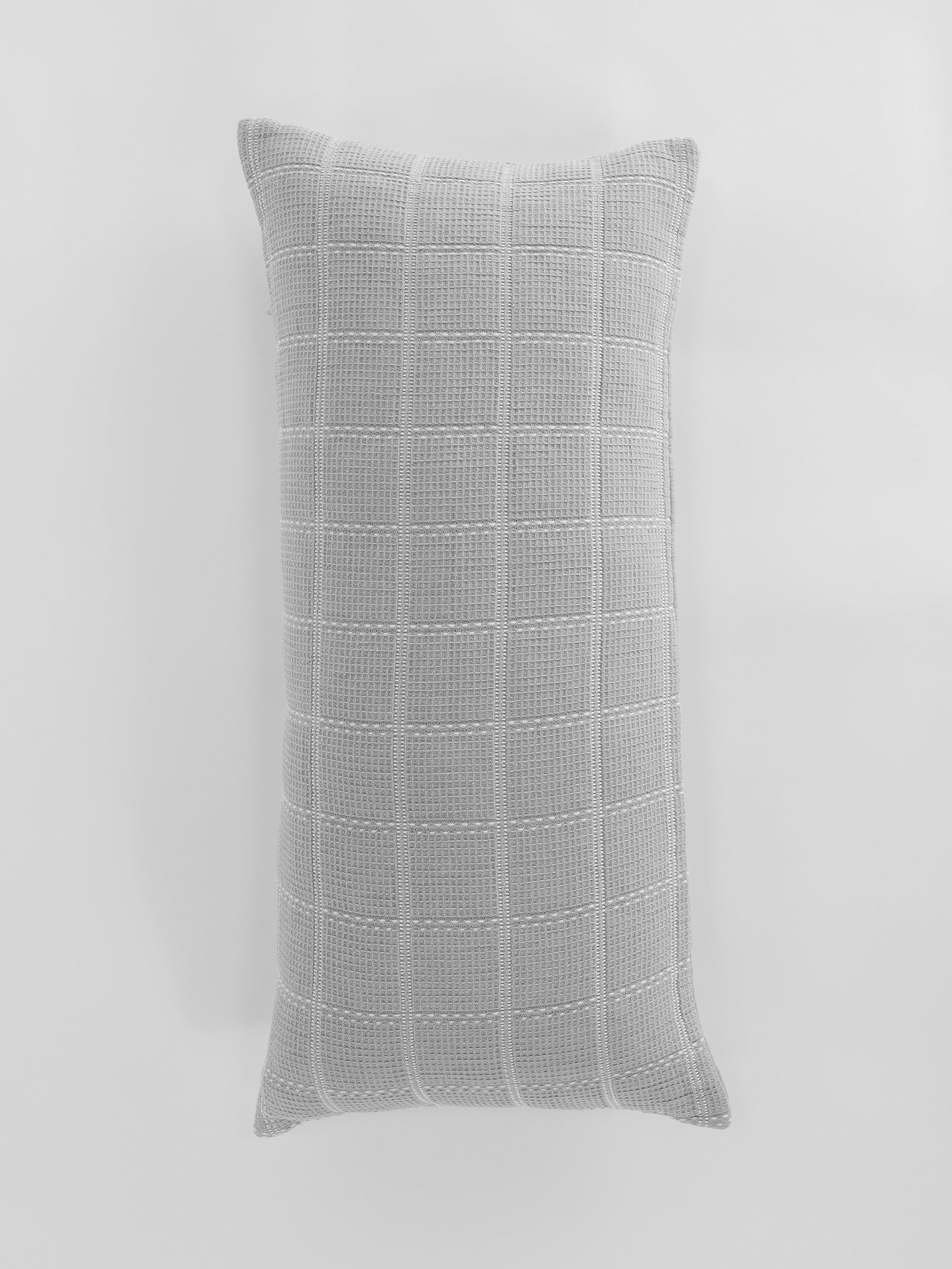 A rectangular Waffle Windowpane Pillow by Cozy Earth, featuring a light gray knitted design with a textured grid pattern against a plain white background. 