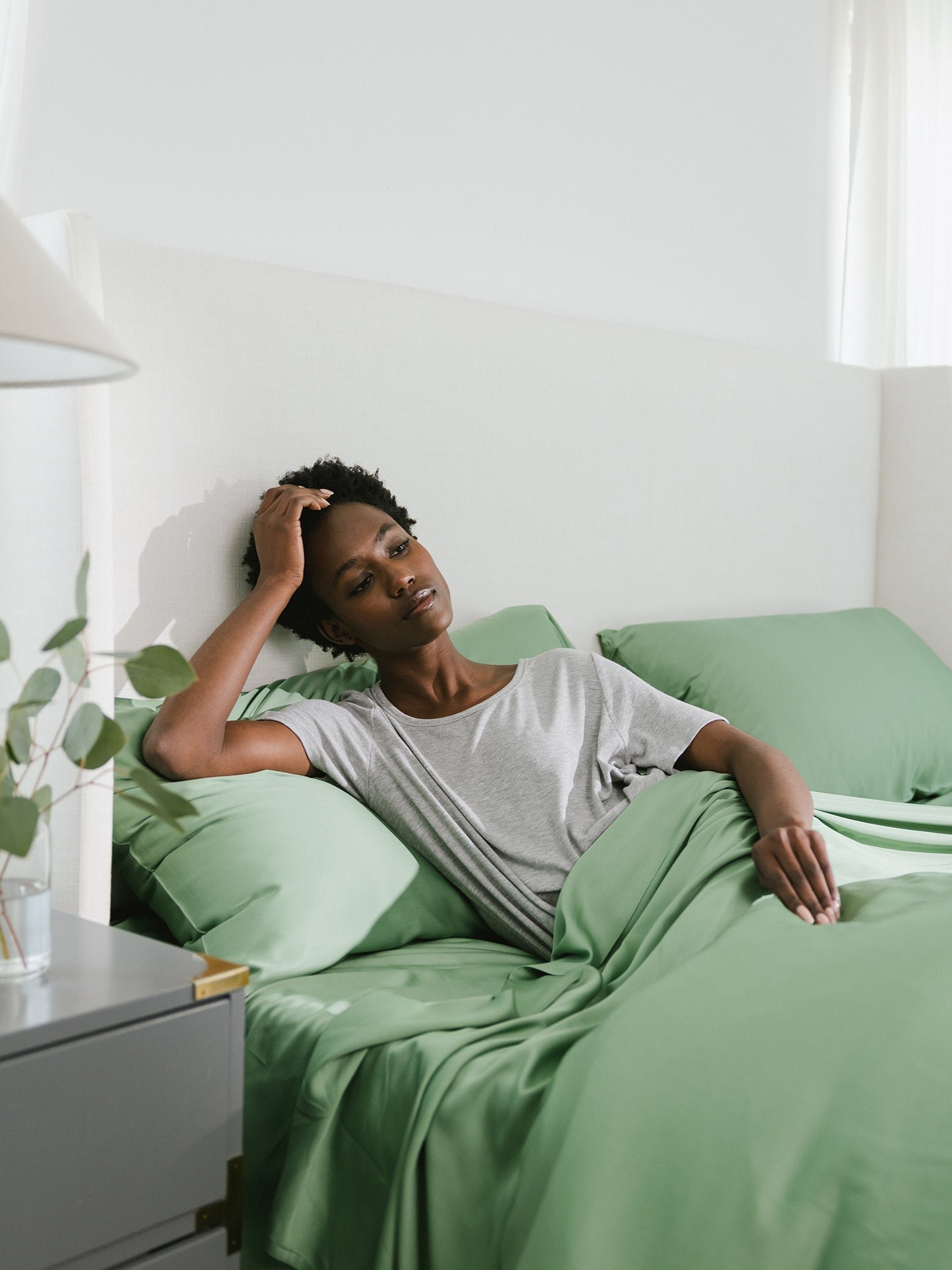 Women sitting on bed with fern colored bedding 