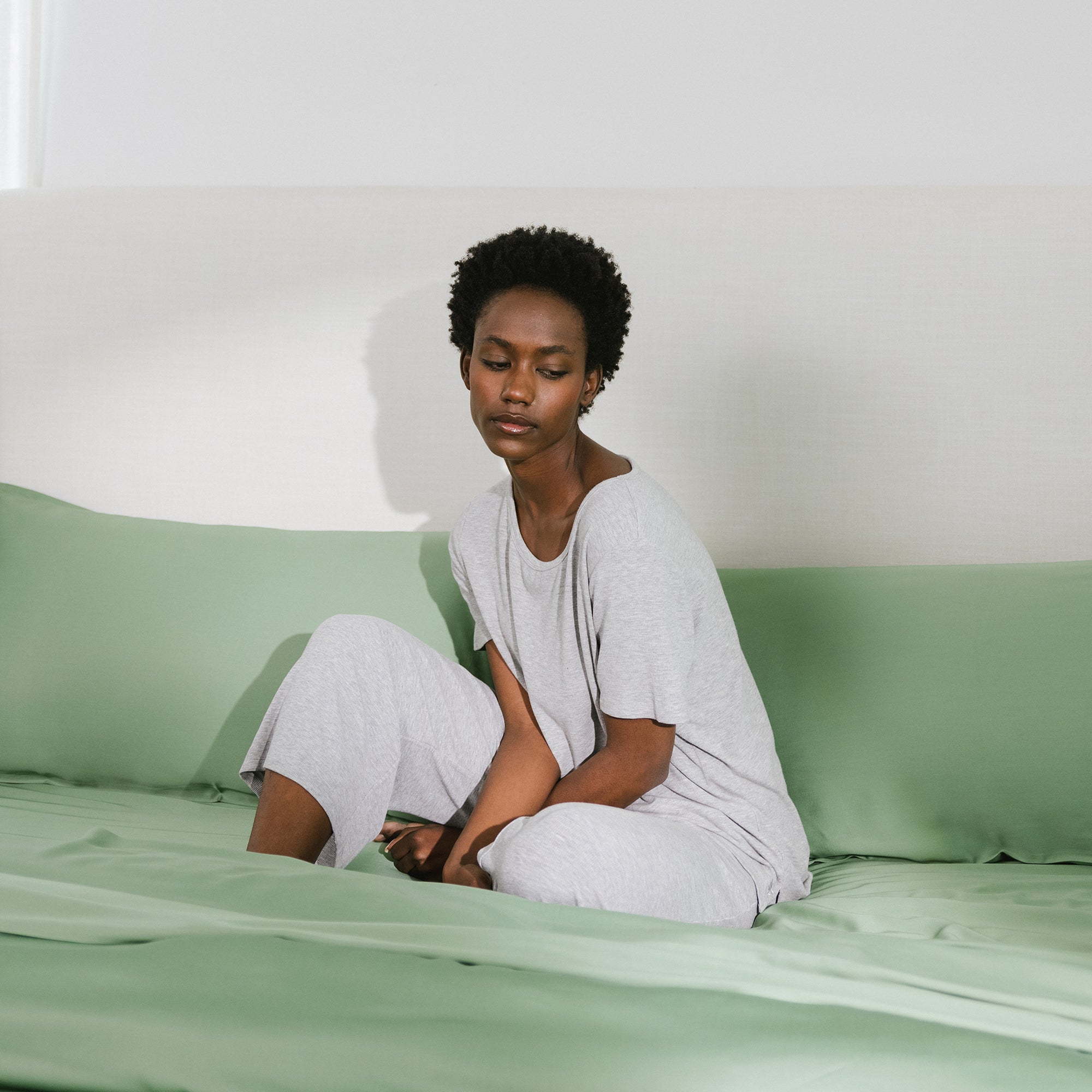 Fern Sheets on bed. A woman lays on the bed standard/king. 