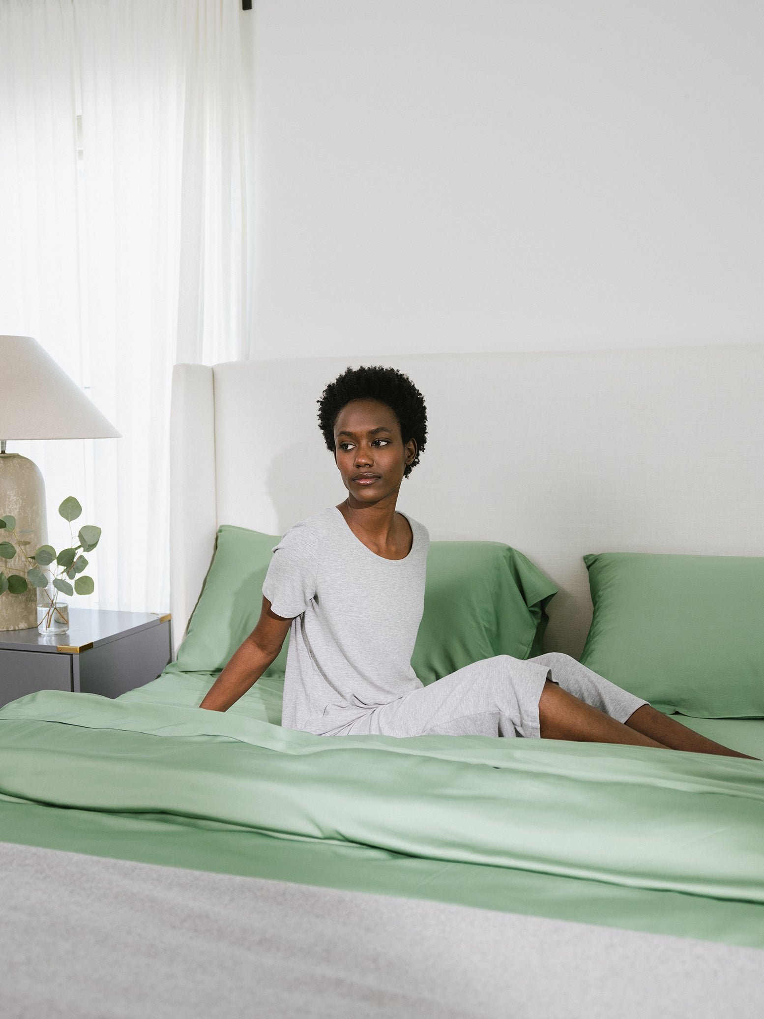 Women sitting on bed with fern colored bedding 