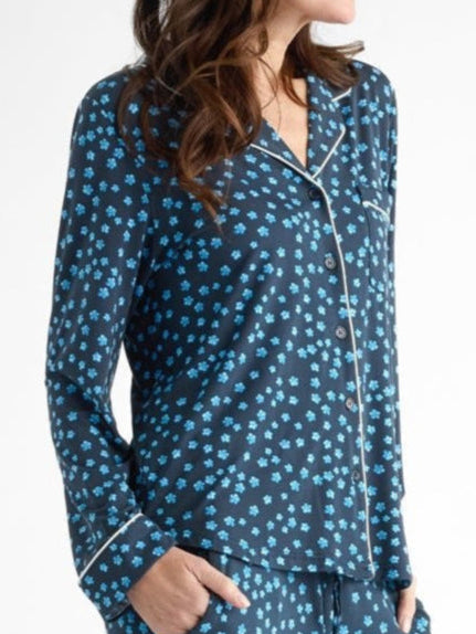 Person wearing a blue pajama set with white polka dots, standing with hands in pockets against a plain white background.
