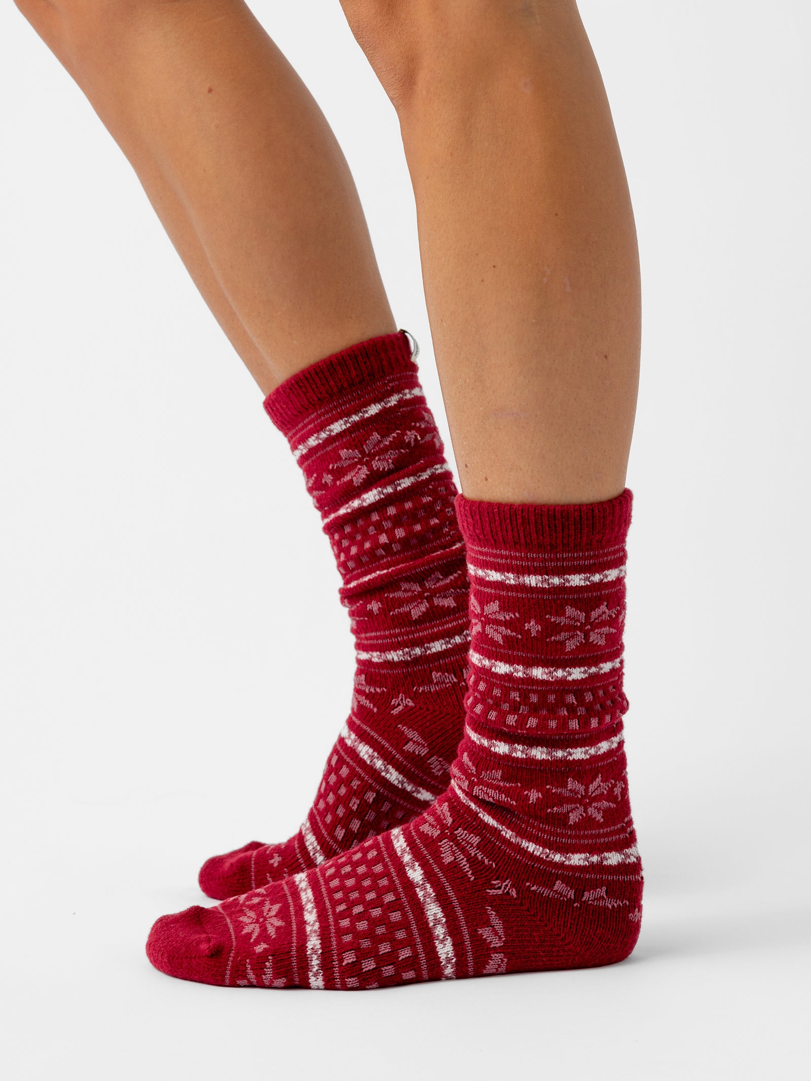 A person stands sideways with a white background wearing Snowflake Plush Lounge Sock in Garnet 