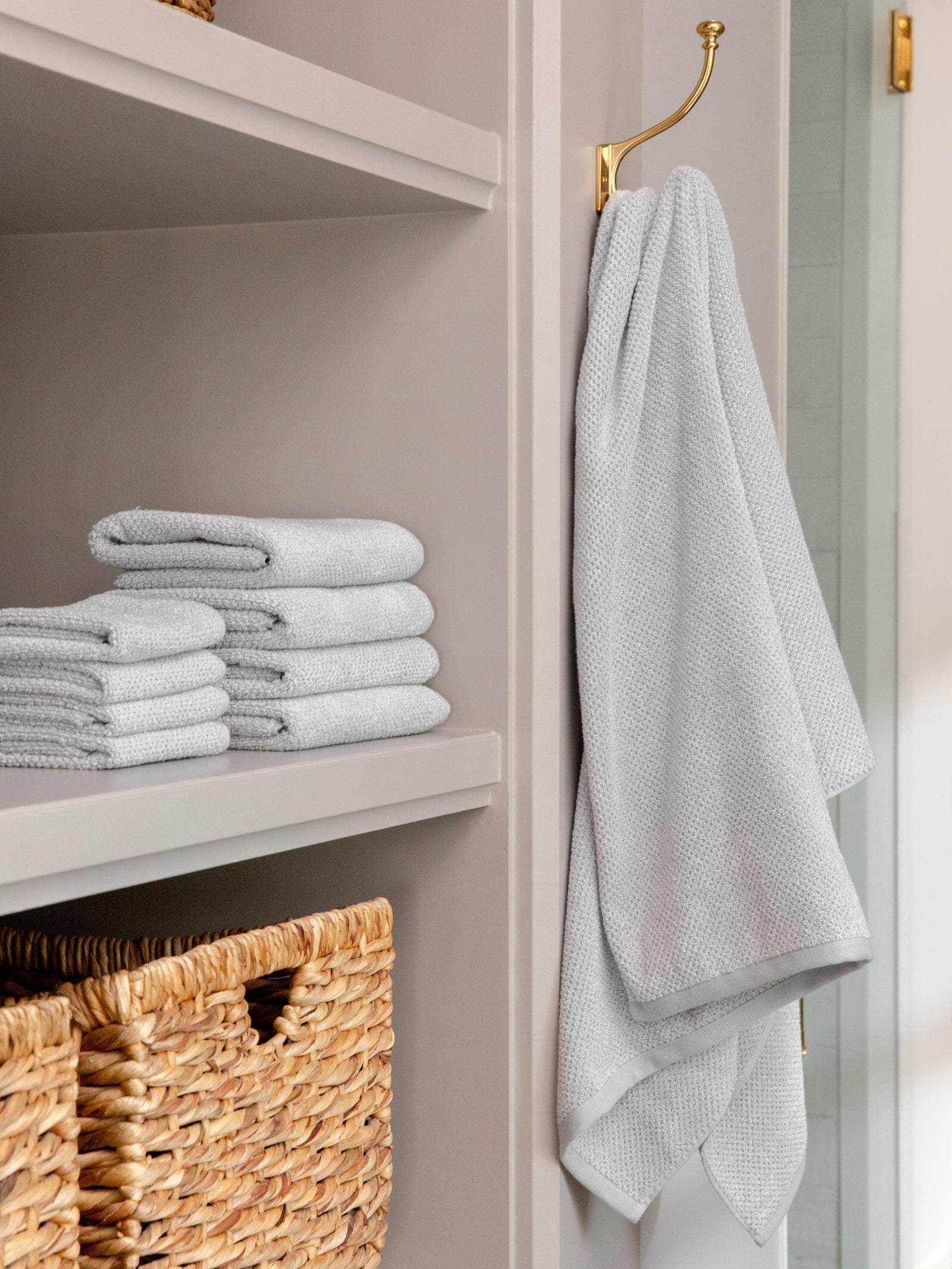 Nantucket Bath Sheets in the color Heathered Harbor Mist. Photo of Nantucket Bath Sheets taken as Nantucket hand towels, wash clothes, and bath towels are neatly placed on shelves in a bathroom. 