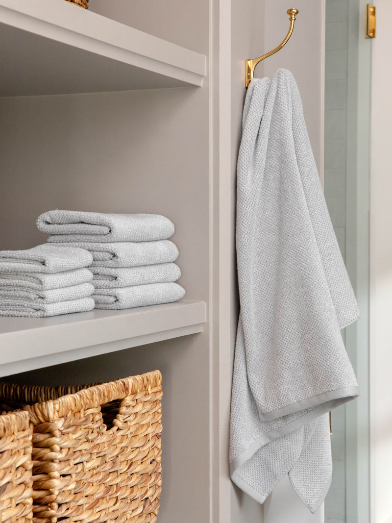 Nantucket Bath Sheets in the color Heathered Harbor Mist. Photo of Nantucket Bath Sheets taken as Nantucket hand towels, wash clothes, and bath towels are neatly placed on shelves in a bathroom.