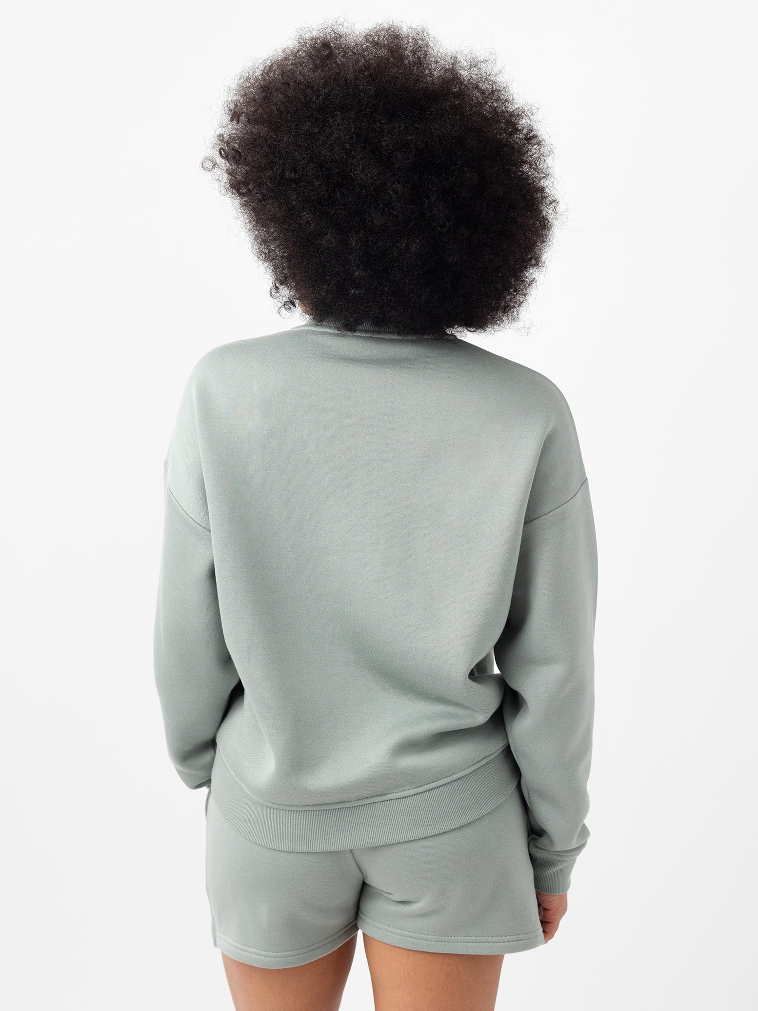 Haze CityScape Pullover Crew. The Pullover is being worn by a female model. Accompanying city scape clothing is being worn to complete the look of the outfit. The photo was taken with a white background. 