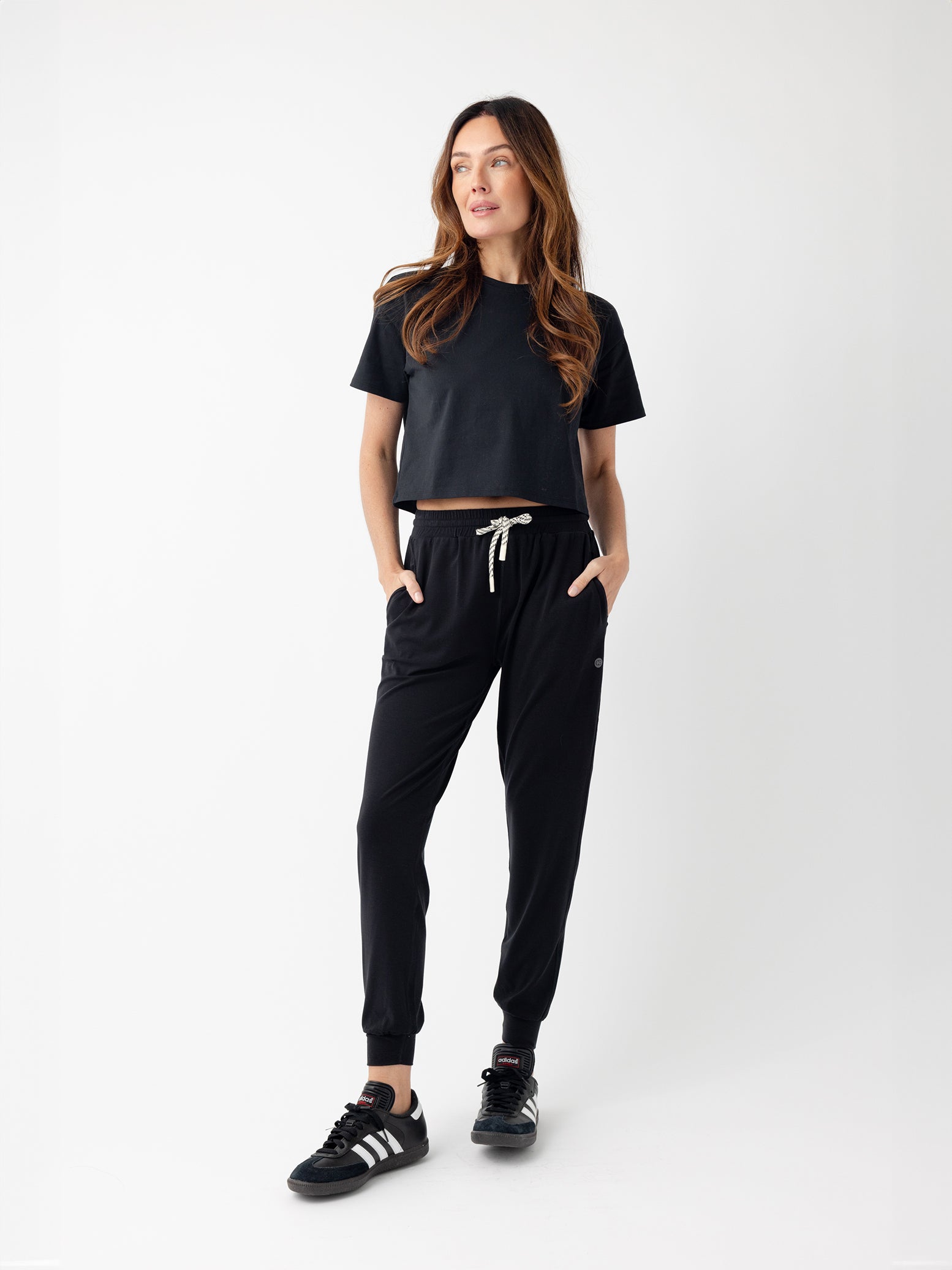 Jet Black All Day Cropped Tee. The photo of the All Day Cropped Tee is taken with a with a white background and is worn by a woman. 