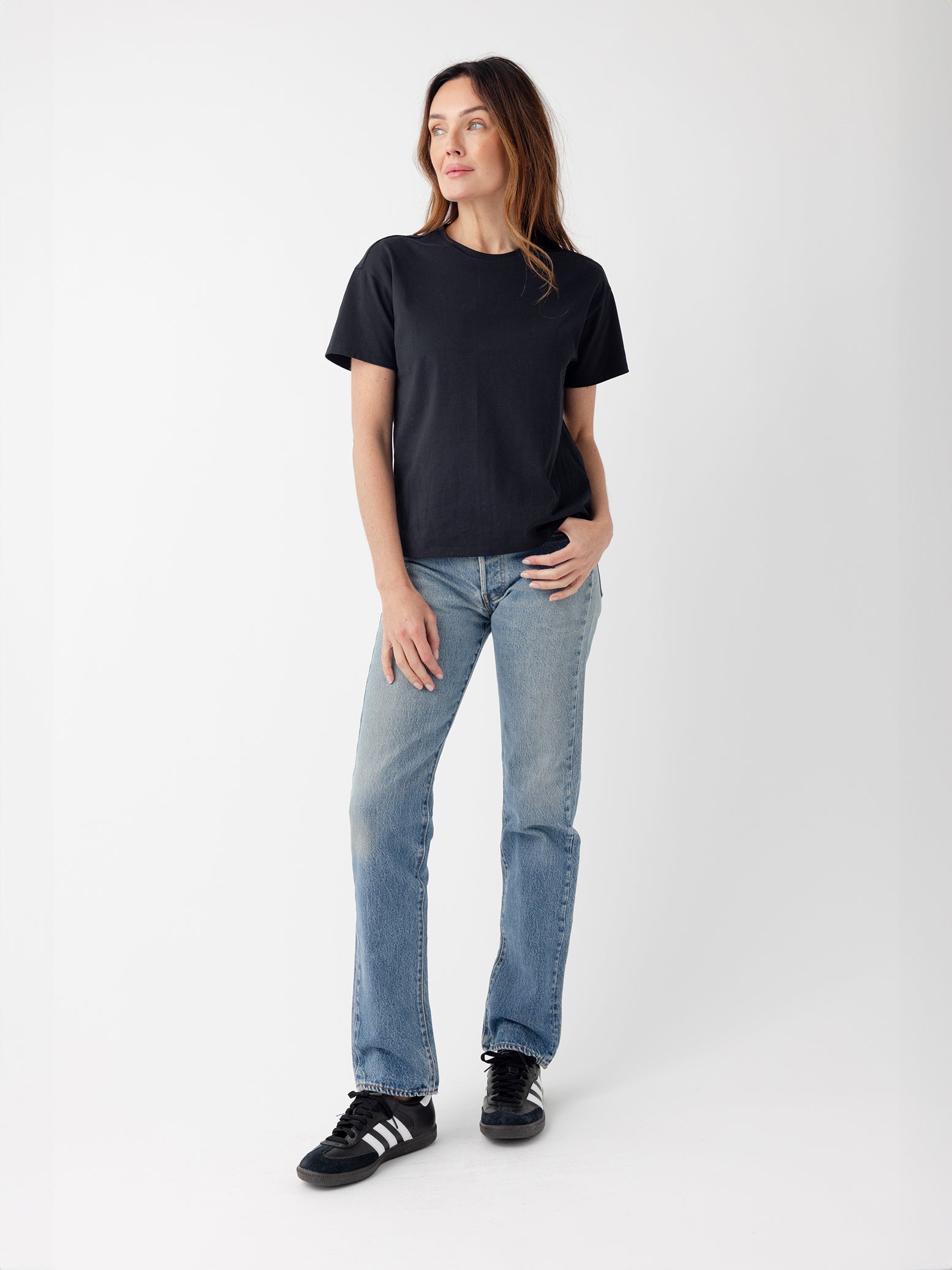 Woman wearing black tee and jeans with white background 
