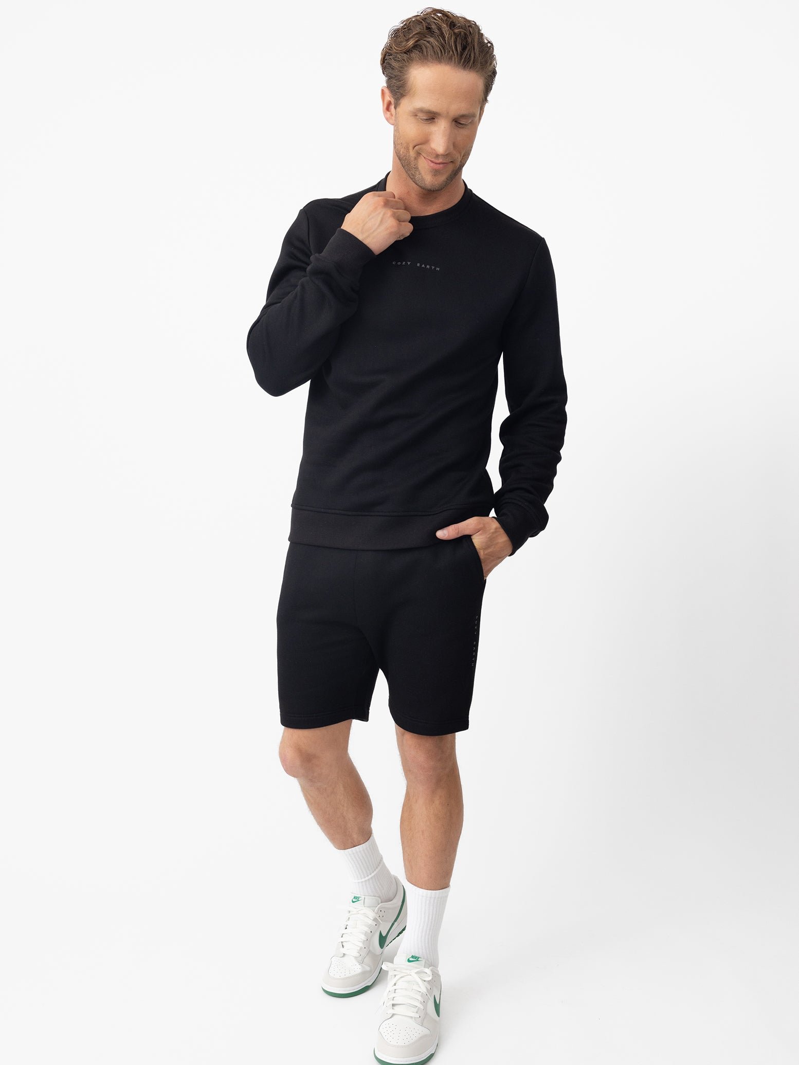 Man wearing black cityscape pullover and shorts with white background 