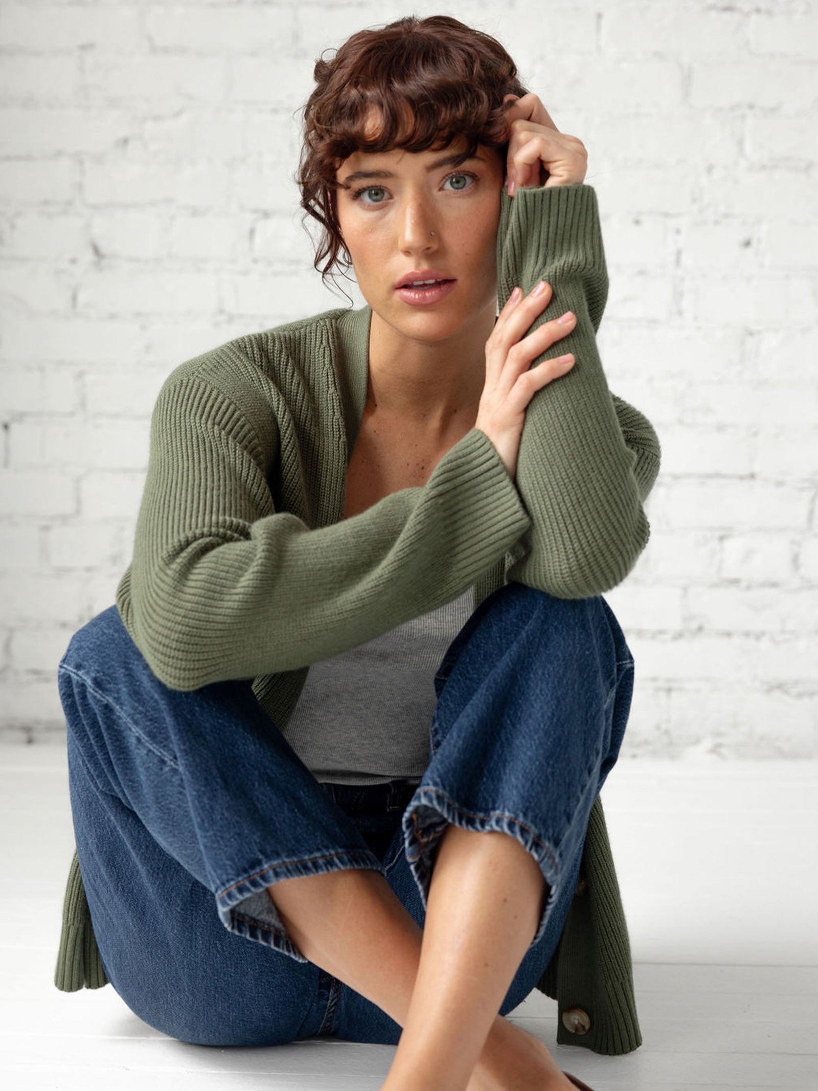 Woman sitting on floor in jeans and juniper cardigan 
