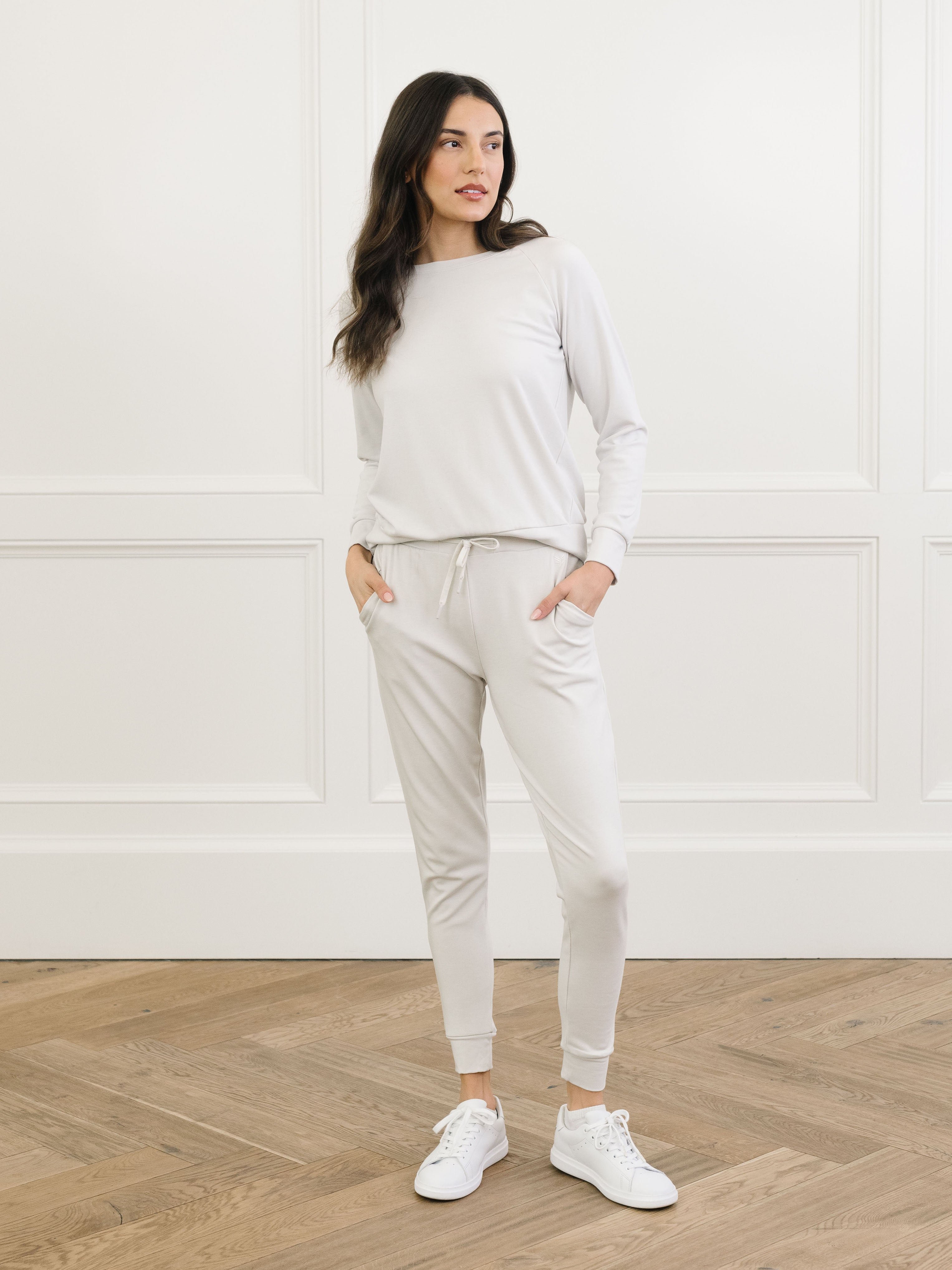 Light Grey Bamboo Jogger Set modeled by a woman. The photo was taken in a high contrast setting, showing off the colors and lines of the pajamas. 
