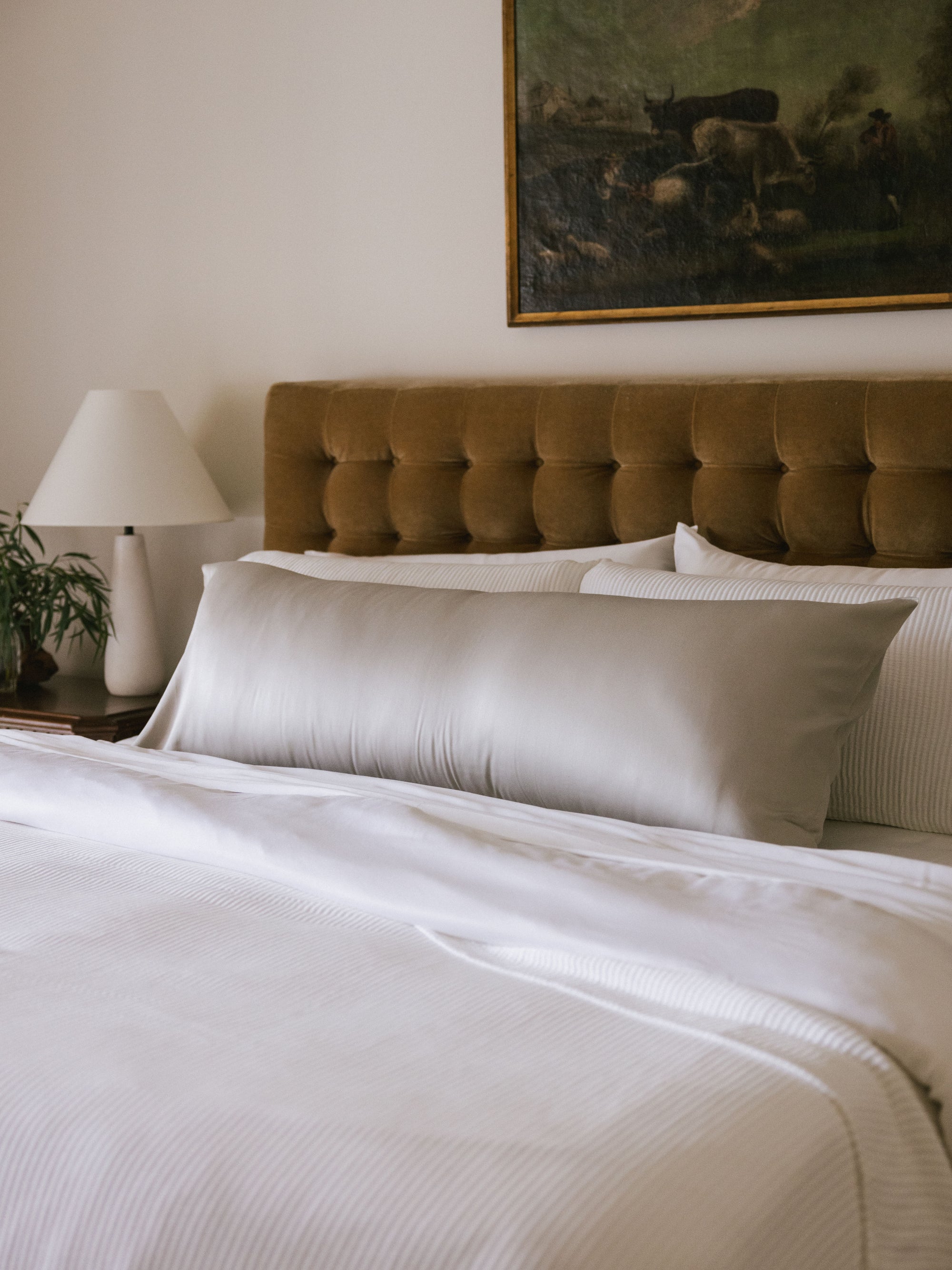 Body pillow with light grey case on bed 