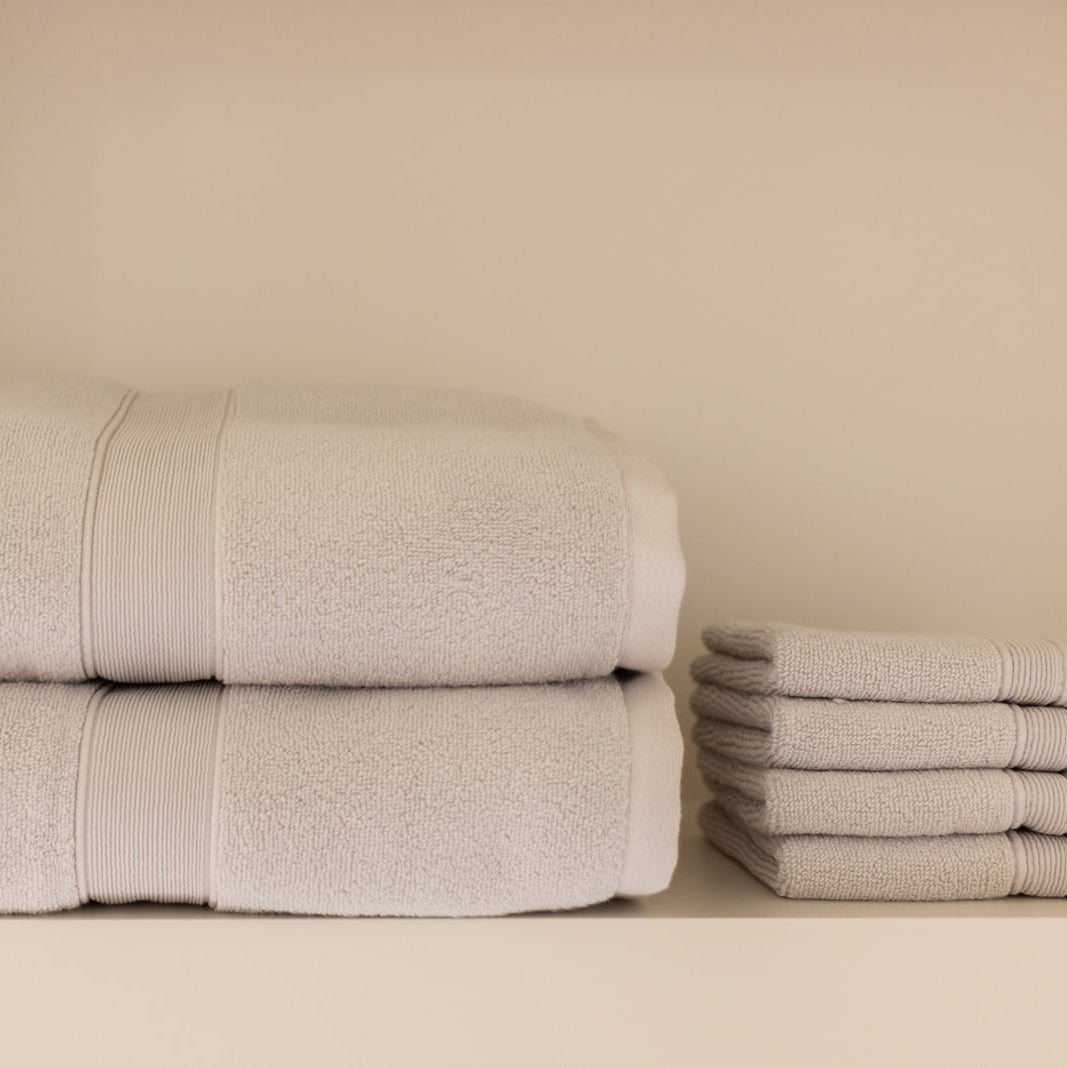 Light grey luxe towels and washcloths folded on shelf 