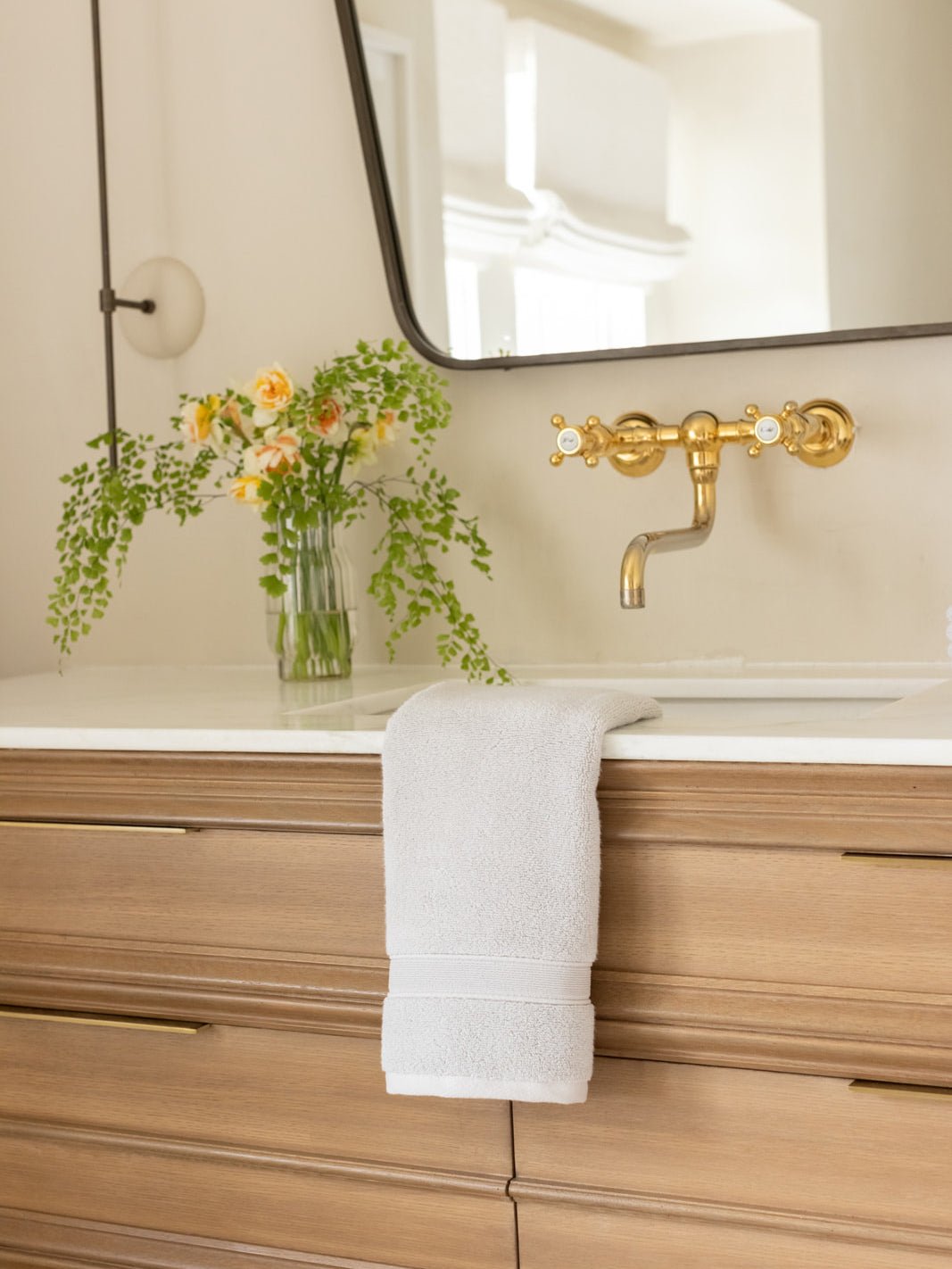 Light grey hand towel draped over bathroom sink 