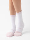 Close-up of a pair of legs wearing white Essential Calf Socks from Cozy Earth, featuring light pink toe and heel accents. The socks have a ribbed texture around the ankles and the word "Nike" written near the toes. The background is plain white. |Color:Lilac