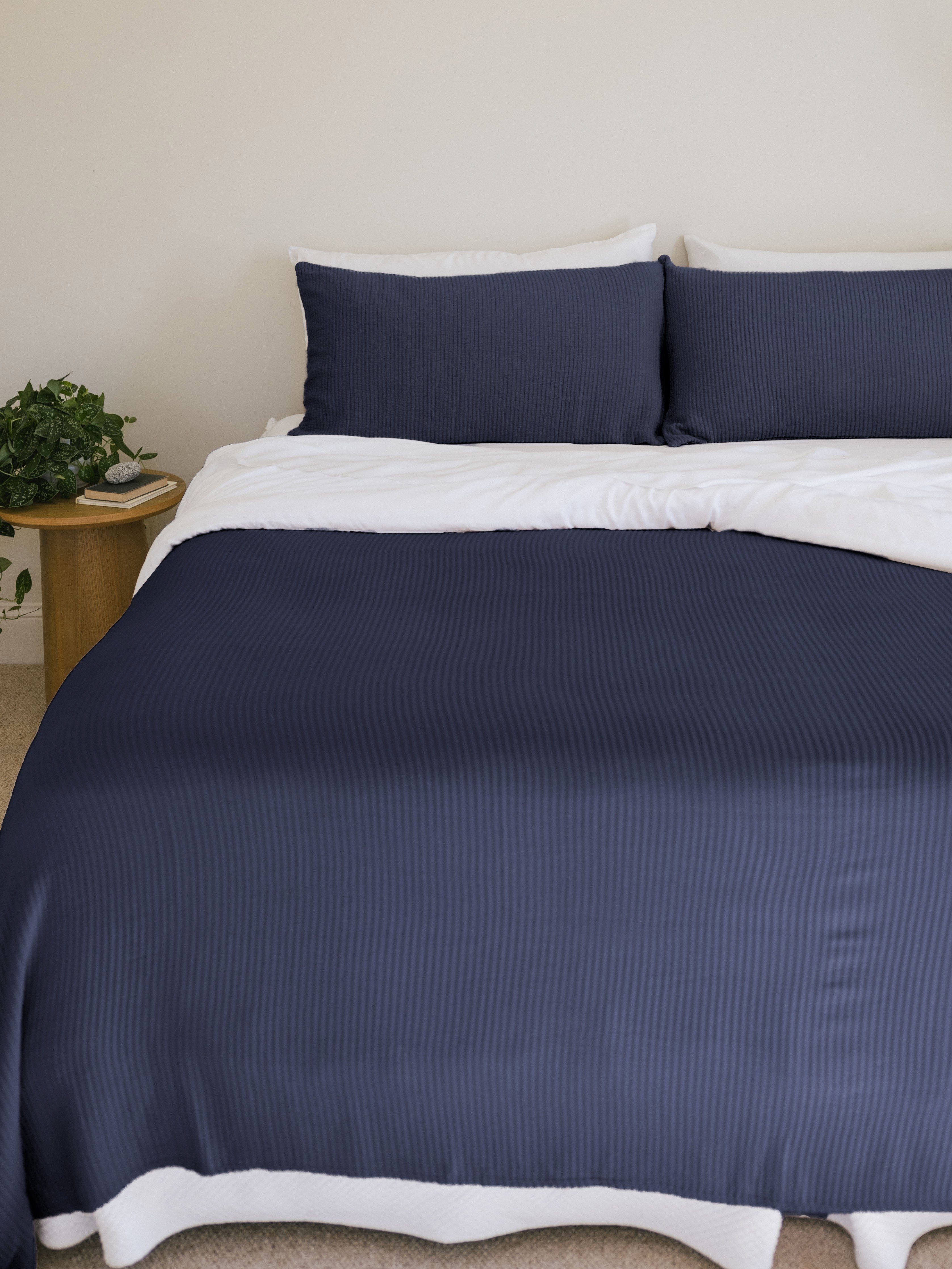 Navy coverlet and shams on a bed 
