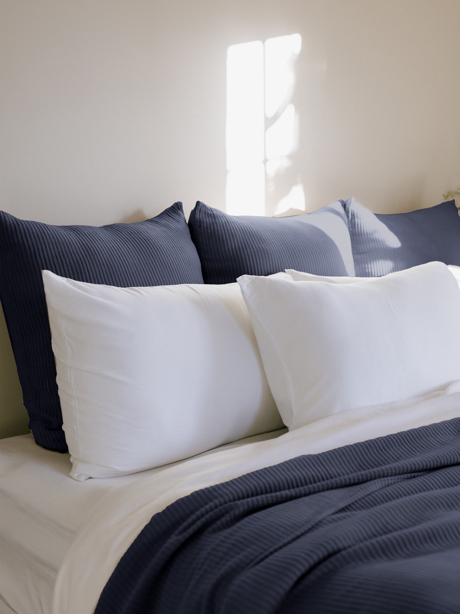 Navy euro coverlet shams behind white pillows on bed 