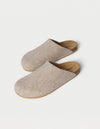 The Lakehouse Clog by Cozy Earth are beige woolen slip-on slippers with a cork sole, viewed from above. They feature a minimalist design perfect for indoor use against a light cream background. |Color:Oat