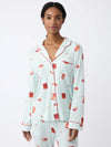 A woman models the Cozy Earth Women's Long Sleeve Bamboo Pajama Top in Stretch-Knit. The pajamas are light blue with red piping and feature a red book print. She stands against a plain white background, smiling slightly at the camera. |Color:Perfect Match
