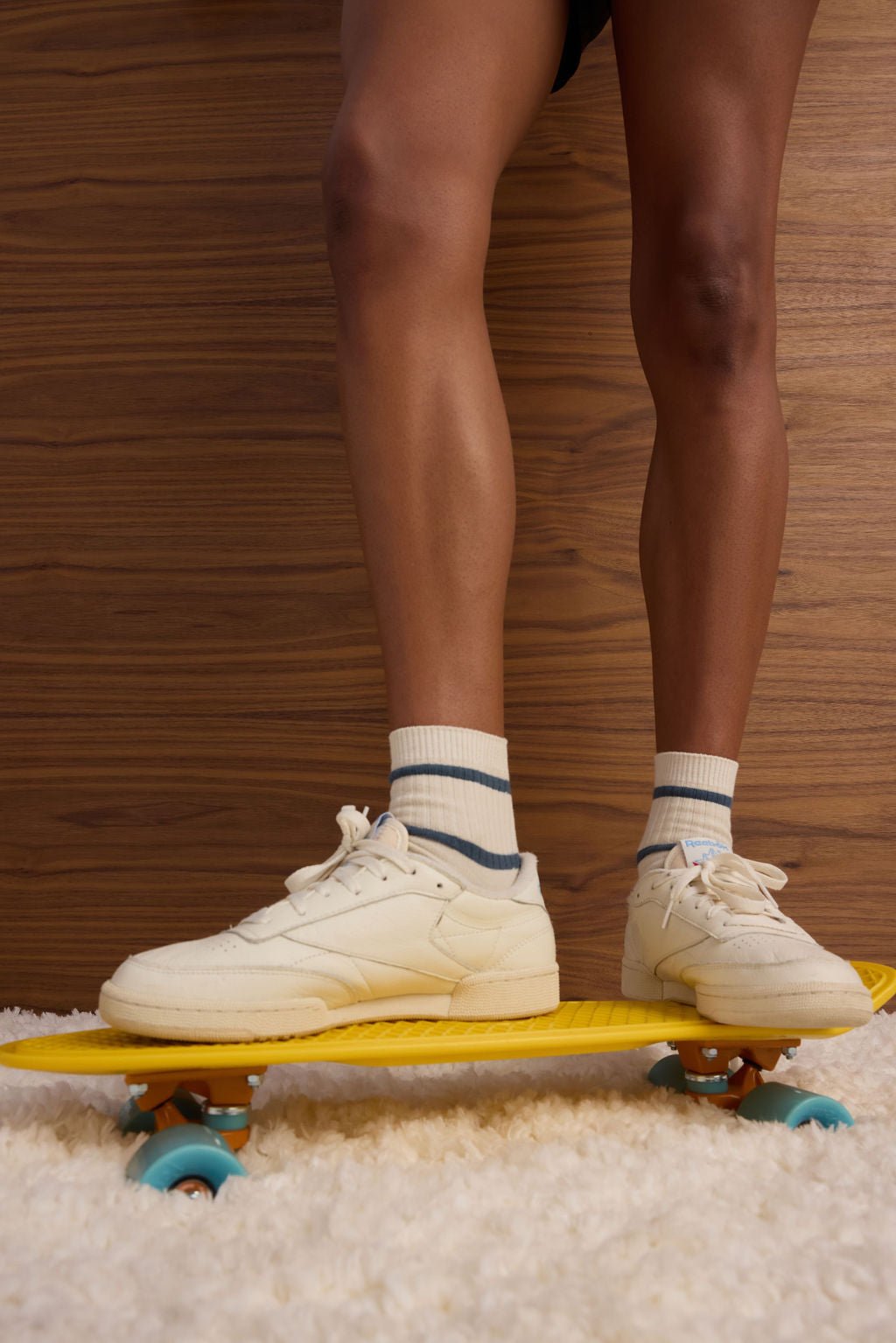 A person wearing Cozy Earth's Women's Sadie Sock in cream with dark blue stripes is shown on a skateboard. 