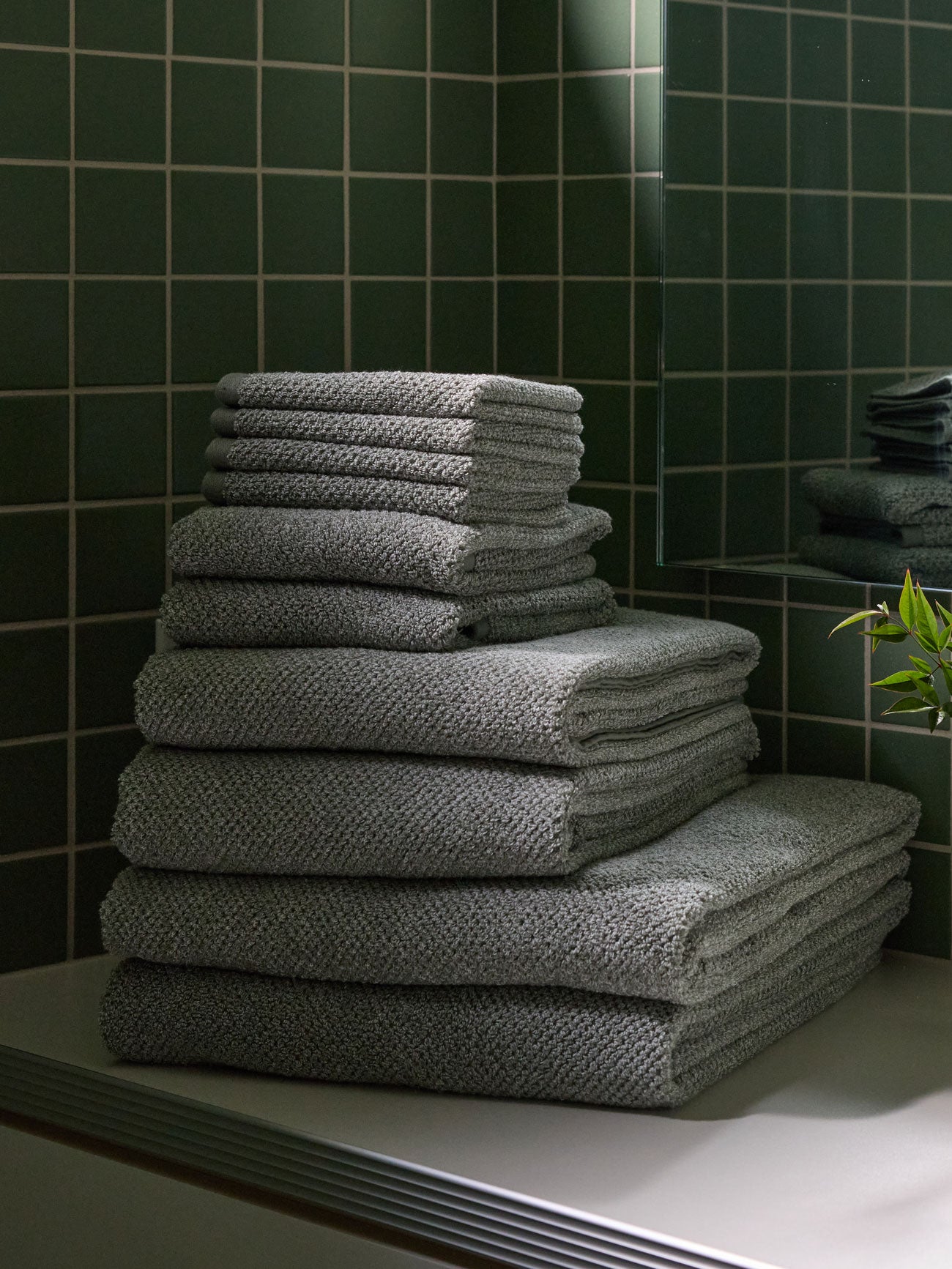 The Complete Nantucket Bath Bundle is shown sitting on a bathroom vanity countertop with a green tiled wall in the background. 