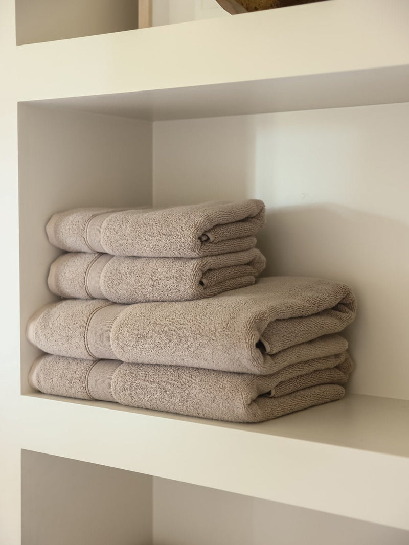 Sand luxe bath towels and hand towels folded on shelf